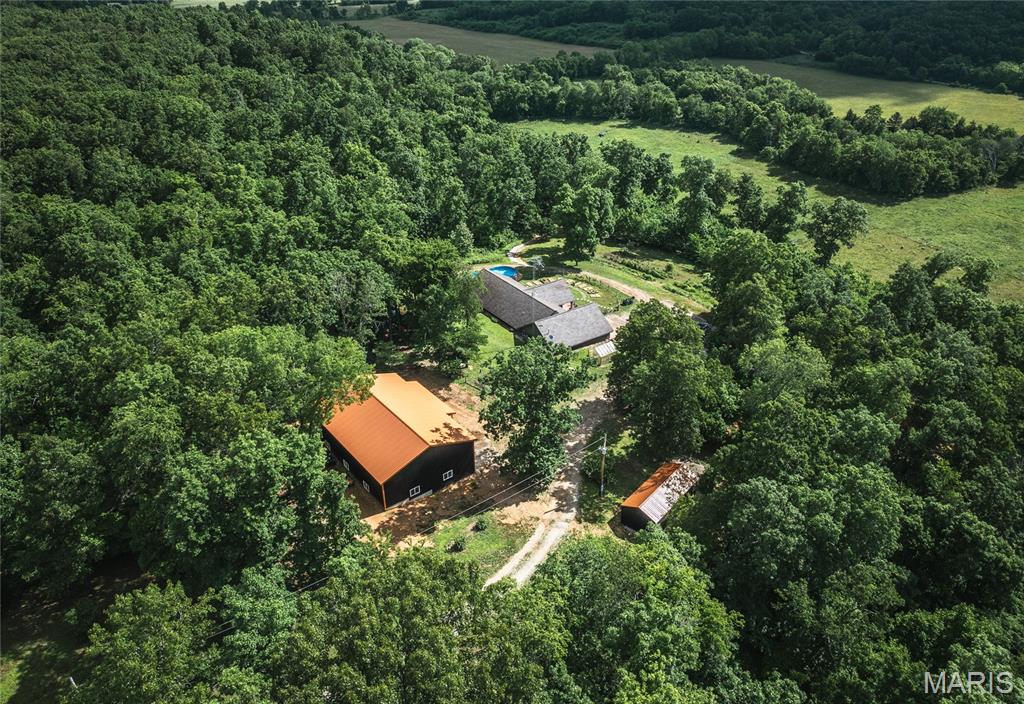 Perched atop a scenic hill with breathtaking views of the surrounding countryside, this remarkable 3-bedroom, 2-bath home offers the perfect blend of comfort, self-sufficiency, and rural charm. Situated on the headwaters of the Meramec River, the property features approximately 25 acres of fertile tillable bottom ground along with additional pasture and wooded acreage, creating endless opportunities for farming, recreation, and outdoor living. Thoughtfully designed for efficiency and peace of mind, the home is equipped with multiple heating options, including an electric heat pump, propane furnace, and a Hardy outdoor wood stove that also supplies hot water. The kitchen is ready for your preferred cooking style with both an electric range and a propane hookup available. The mechanical room includes a water filtration system, water softener, and UV light system for added convenience. Inside, expansive windows frame stunning hilltop views while filling the home with natural light. Cozy gas fireplaces anchor both the living room and primary suite, creating warm and inviting spaces to unwind. The spacious primary retreat also features a walk-in dressing room, deep soaking tub, and separate shower. Step outside to discover approximately 10 acres of cross-fenced pasture complete with water and electric service, multiple water spigots, fruit trees, garden plots, a 40-foot above-ground pool, and a brand-new 40x60 shop with power, electric, and 16-foot doors built in 2025. Additional wooded acreage across County Road 5380 provides even more room to explore and enjoy. Whether you're seeking a working hobby farm, a private homestead, or a peaceful country escape, this extraordinary property offers a lifestyle that's becoming increasingly difficult to find. Schedule your private tour today and experience it for yourself.