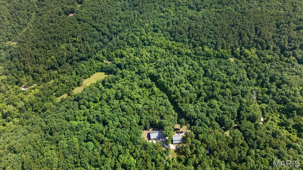 **YOUR OWN 67-ACRE MISSOURI ESCAPE—ABOUT AN HOUR FROM ST. LOUIS!** Trade traffic, schedules and neighbors for wooded trails, wildlife and weekends spent outdoors. Tucked away at the end of a long private drive, this secluded hilltop retreat offers approximately 67 acres of predominantly wooded countryside to hunt, ride, hike, explore and enjoy.

Perched along a scenic ridge, the 2,200+ sq. ft. home provides a comfortable place to gather after a day outdoors. The wraparound porch is made for slow mornings, evening sunsets and taking in the peace and quiet. Inside, an open floor plan connects the spacious living, dining and kitchen areas. The main level includes the primary bedroom, full bath, laundry and utility room, while upstairs you'll find two additional bedrooms, a second full bath and versatile bonus room—plenty of space for family, friends and overnight guests.

But the land is the real attraction. An established trail system winds through rolling wooded terrain with two creeks, multiple deer stands and plenty of room for ATVs, hiking, target shooting and exploring. Years of trail-camera photos document the wildlife that call the property home, adding to its appeal as a hunting and recreational retreat.

Bring the ATVs, side-by-sides, tractor, hunting gear and outdoor toys. The impressive 40' x 40' insulated outbuilding features electric service, concrete floors and three 10' x 12' overhead doors, providing exceptional space for equipment, recreational vehicles, workshop projects and storage.

Whether you're searching for a weekend getaway, hunting property, recreational retreat or simply your own private piece of Missouri countryside, this is a property designed to be enjoyed in every season. **Far enough away to feel like you've escaped. Close enough to use every weekend.**