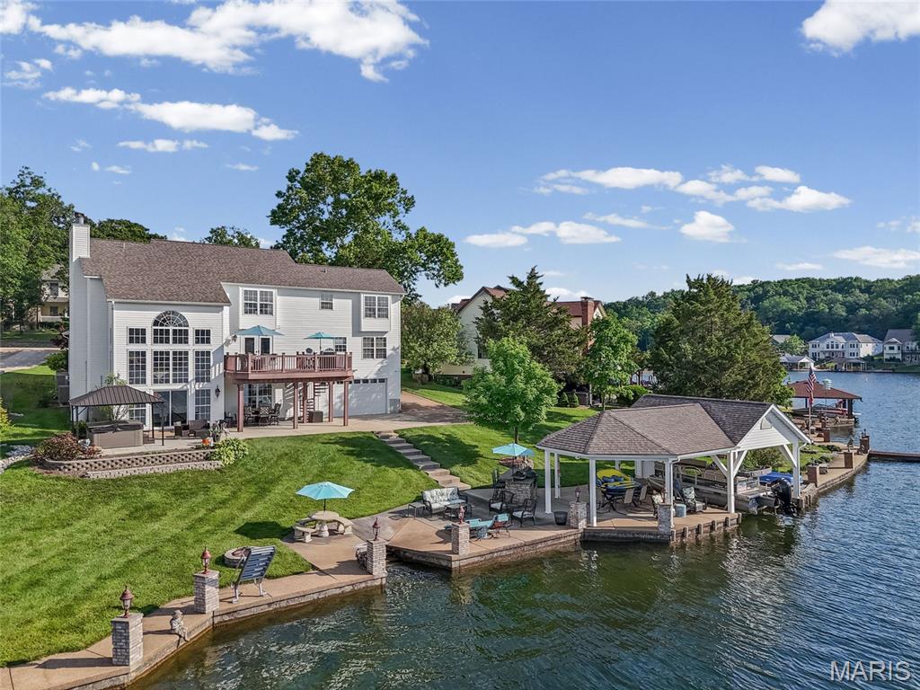 Poised on one of the most coveted waterfront settings in Raintree Plantation, this extraordinary Atrium Ranch commands a rare double waterfront lot with breathtaking panoramic views across the 127±-acre Autumn Lake. Here, each sunrise unveils a new masterpiece, while every sunset transforms the lake into nature’s canvas as the ever-changing sky is reflected across the water, creating the breathtaking illusion that the sky and lake become one.

Designed to embrace its spectacular setting, this true Atrium Ranch showcases dramatic walls of glass that capture stunning lake views from nearly every vantage point. Elegant wrought-iron staircases surround the signature atrium and lead to the open loft overlooking the soaring great room below. The timeless Old Chicago brick exterior reflects exceptional craftsmanship and enduring architectural appeal.

A grand two-story foyer with a dramatic dual-balcony loft welcomes you into thoughtfully designed living spaces filled with natural light. The formal dining room is ideal for elegant entertaining, while the spacious breakfast room flows seamlessly into the gourmet kitchen. Anchored by an oversized center island, the kitchen is appointed with premium stainless steel appliances, a custom cooktop, built-in wine cooler, and a Sub-Zero refrigerator that conveys with the home, creating the perfect space to gather with family and friends while exploring your culinary creativity.

The magnificent great room features soaring cathedral ceilings, one of two fireplaces, and a breathtaking wall of windows that brings the beauty of the lake indoors throughout every season. The luxurious main-level primary suite offers a peaceful retreat with a spa-inspired en-suite bath, while a handsome library and convenient main-floor laundry complete this level.

The upper level features an open loft overlooking both the great room and the shimmering lake beyond, accompanied by three spacious guest bedrooms, a full guest bath, and a study.

The finished walkout lower level offers the ambiance of a private lakefront resort. A spectacular custom-built bar serves as the centerpiece for entertaining, while the second fireplace creates the perfect setting for relaxing after a day on the water. A full bath, abundant storage, and an additional four-car lower-level garage provide exceptional space for boats, golf carts, watercraft, collector vehicles, or the ultimate workshop.

The exterior is every bit as impressive as the interior. Professionally designed, estate-quality landscaping and gently terraced grounds lead effortlessly to the shoreline. A sprawling composite deck and massive covered patio provide multiple spaces to relax, entertain, and enjoy the ever-changing views.

At the water’s edge awaits an extraordinary private boathouse that is truly a retreat within itself. Complete with a covered boat slip, built-in entertainment, a waterside dining area, and an expansive lakeside patio, it creates the ultimate destination for unforgettable gatherings, peaceful afternoons, and evenings spent enjoying the beauty of Autumn Lake.

As remarkable as the home itself are the unforgettable moments it offers. From peaceful mornings on the composite deck to evenings spent at the private boathouse, every day is framed by breathtaking panoramic views and spectacular sunsets. Here, Autumn Lake becomes nature’s canvas as the  ever-changing sky is reflected across the water, creating the breathtaking illusion that the sky and lake become one. This is more than a home—it is where generations will gather, traditions will begin, and memories will be written against one of the most spectacular backdrops on the lake.
"Give Your Dream A New Address - 9609 East Vista "