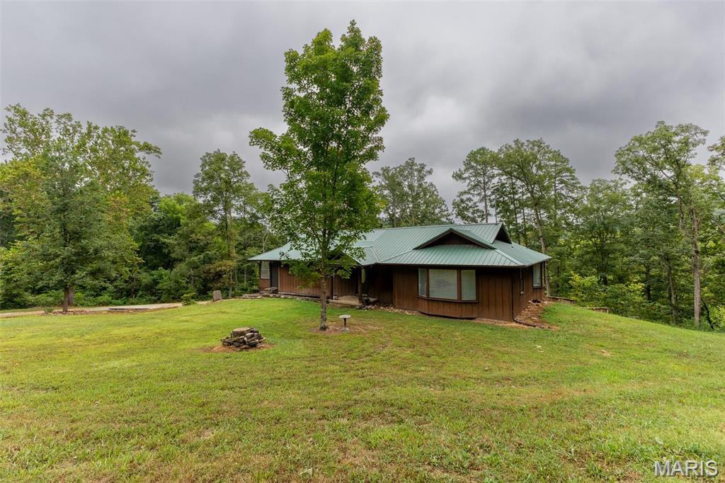 Skyfall Ranch is a private country retreat on 58 acres m/l featuring Mullins Creak a year-round live creek, small pond, rolling pasture, mature hardwoods, and abundant wildlife. Located near the Big Piney River, Roaring Springs, Montauk State Park, Sandy Shoals Ford and close to other conservation areas and state parks, this 5-bedroom, 3-bath home offers 2,706 sq. ft. of comfortable living with stunning countryside views from large bay windows in the dining room, living room, and primary bedroom. Interior features include cedar plank flooring, concrete countertops, kitchen island, walk-in pantry, sunroom, two living areas, bonus rooms, and a basement kitchenette ideal for guests or multi-generational living. Enjoy outdoor living on the covered patio or deck overlooking the creak. The property also includes a barn/shop with lean-to, 2-car garage, chicken coop, dog kennel, fire pit, deer blinds, and plenty of room for livestock, hunting, farming, or recreation. Skyfall Ranch offers the perfect blend of privacy, nature, and country living.