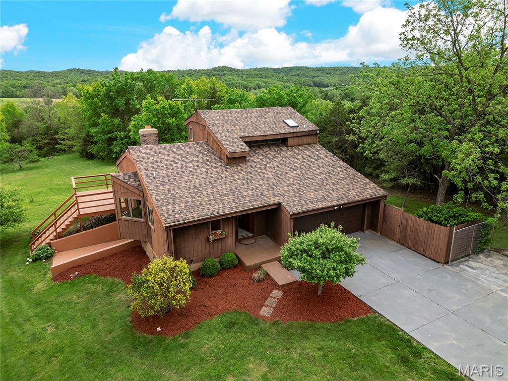 Rarely does an opportunity like this come available in Defiance! Located in the beautiful Femme Osage valley, nestled on approximately 9 picturesque acres, this 3 bed, 2.5 bath home offers the perfect blend of privacy, space, and everyday comfort. Step inside to find hardwood floors throughout the main level, leading to a well-appointed kitchen featuring granite countertops and stainless-steel appliances. The main floor primary suite provides convenience and retreat with a private bath, while upstairs offers two spacious bedrooms and a full bath! The finished lower level adds additional living and entertaining space, complete with built-in shelving for your media setup. One of the true highlights of the home is the stunning four seasons room with floor-to-ceiling windows and skylights, bringing in natural light and offering year-round views of the surrounding landscape. Step outside to the expansive wrap-around deck—perfect for enjoying everything this incredible property has to offer. With an attached 2-car garage and ample driveway parking, this property combines functionality with a truly rare acreage setting you won’t want to miss.