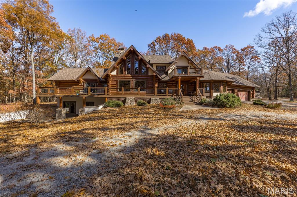 Step into a true Montana masterpiece — a stunning log home boasting over 4,000 finished square feet of rustic elegance and cinematic charm. From the moment you arrive at the end of a nearly mile-long private drive, surrounded by picturesque farmland, you’ll know you’ve found something extraordinary.
The grand family room will take your breath away with its soaring timber ceilings, massive windows, and incredible craftsmanship, including the 2 story stone fireplace. A lofted recreation area with an en suite bath and living room overlooks the living space below, while the main level features a luxurious master suite complete with a spa-like bath retreat. The finished walkout basement offers even more entertaining space, including a lux bunk room and an authentic saloon — perfect for gathering with friends after a day spent exploring your 30-acre private paradise. Every inch of this home showcases the artistry of Montana log construction — tall timbers, exposed beams, and natural textures that feel straight out of a Taylor Sheridan series. (Seriously, someone call Taylor — he needs to see this place!) Imagine spending your days surrounded by nature—riding along peaceful trails that wind through the woods, then watching your horses graze in the sunlit paddocks below. This property is a dream come true for horse lovers, thoughtfully designed with space to roam and relax. With countless porches tucked beneath the trees, you’ll always have the perfect spot to sit back, sip your drink, and take in the beauty of every season. Outside, you’ll not only find many expansive porches but also, a 3-car attached garage, and a 36x36 barn with stalls and a tack room. This is more than a home — it’s an experience. A rare blend of luxury, privacy, and the rugged beauty Montana is known for- right here in Missouri. This one must be seen to be truly appreciated.