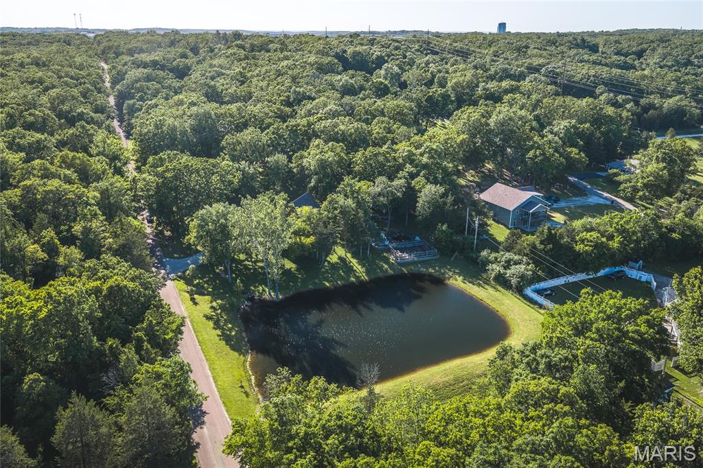 Located just outside the city limits of Rolla, this exceptional custom-built home offers the perfect combination of privacy, luxury, and convenience, with shopping, dining, and everyday amenities only minutes away. Nestled in a peaceful setting surrounded by abundant wildlife, the property provides a true country retreat while remaining close to town. The home is filled with natural light and showcases quality craftsmanship throughout, featuring granite countertops, custom cabinetry, and thoughtfully designed living spaces. The spacious primary suite is a private sanctuary with a luxurious master bath complete with a two-person walk-in tiled shower, Jacuzzi tub, dual vanities, and an oversized walk-in closet. Step outside and enjoy the impressive outdoor living areas highlighted by beautiful stonework, durable Diamond Kote siding, stamped concrete patios, and an oversized covered front porch perfect for relaxing and taking in the scenery. The swimming pool creates an ideal setting for entertaining family and friends during the summer months. Nature lovers and hobby gardeners will appreciate the mature pear, plum, and mulberry trees along with a productive vegetable garden that yields year after year. The stocked pond is a standout feature, offering excellent fishing opportunities with catfish, bass, crappie, perch, and grass carp. Additional features include a spacious 3-car garage, private setting, abundant wildlife, and a property designed for both comfort and enjoyment. Whether you're looking for a forever home, hobby farm potential, or simply a peaceful escape near Rolla, this one-of-a-kind property delivers.
