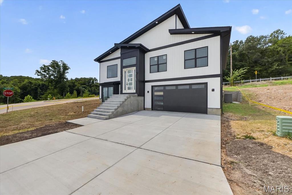 Not your typical new construction. This architect-designed contemporary home was thoughtfully built under the direction of a master civil engineer, with an emphasis on architectural character, quality finishes, energy efficiency, and spaces you simply don't find in a standard production home.

The moment you enter, the 18-foot living room ceiling and dramatic 12-foot-high windows create an impressive, light-filled centerpiece to the home. The open-concept living space is anchored by a modern fireplace and flows directly into a custom kitchen featuring white oak cabinetry, an oversized center island, walk-in pantry, quartz countertops, and a selection of KitchenAid stainless steel appliances.

The true showpiece is the approximately 800-square-foot primary suite—designed as a private retreat rather than simply a bedroom. It features two separate his-and-hers walk-in closets, a spacious private bath, and a distinctive 10'x7' bay-window coffee nook, creating the perfect spot for a morning coffee, reading area, or private sitting space.

With 4 bedrooms and 3 full bathrooms, the home's flexible layout also provides an in-law-style living option, while high ceilings, luxury vinyl flooring, recessed lighting, custom details, and abundant natural light carry throughout the home.

Efficiency was considered alongside design, with an energy-efficient  HVAC system, ENERGY STAR-qualified windows and appliances, smart thermostat, and EV charging capability in the garage. helping bring modern efficiency to this all-electric home.
Outside, the contemporary board-and-batten-inspired exterior, private yard, corner-lot setting, adjoining common ground, and attached two-car garage complete the property.

And the location adds another advantage: approximately 5 minutes from Gravois Bluffs, putting shopping, dining, groceries, entertainment, and everyday conveniences within minutes, while the surrounding area is positioned for continued growth with a new residential development of nearly 100 homes planned nearby.

Architect-designed. Engineer-built. Custom-finished. 986 Hydeaway Ct was created to offer something distinctly different from the typical new-construction home—a combination of dramatic architecture, an exceptional primary suite, custom craftsmanship, modern efficiency, and everyday functionality.