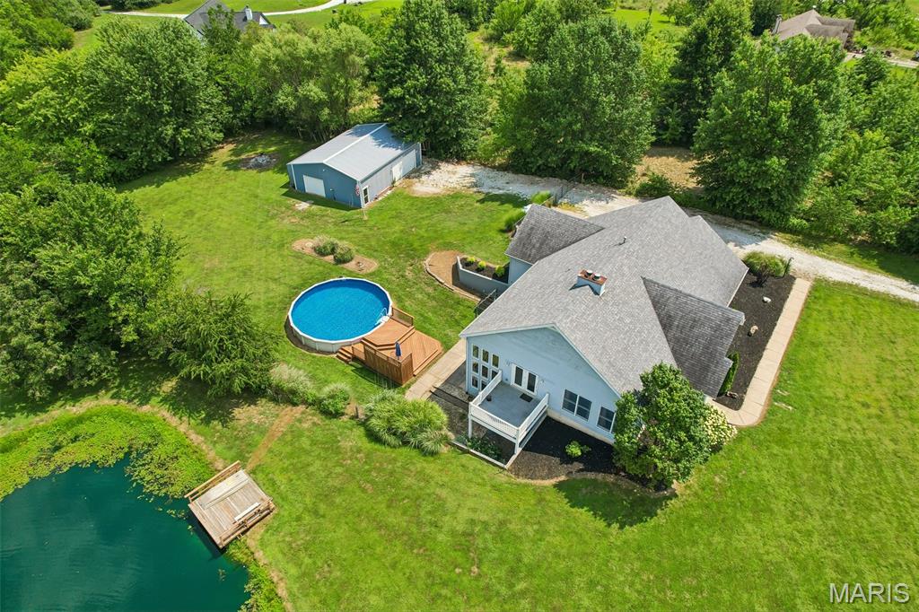 Tucked away on 4.13 picturesque acres in a private Winfield subdivision, this beautifully remodeled 4-bedroom, 3-bath atrium ranch offers the rare combination of luxury, functionality, and country living—all just minutes from shopping, restaurants, and everyday conveniences. With 2,277 square feet above grade, a finished walk-out lower level, a stocked fishing pond, above-ground pool, 30' x 40' workshop, and a fully fenced backyard, this is the kind of property buyers spend years waiting to find.

From the moment you arrive, the home's striking stone facade, architectural roof, fresh landscaping, covered front porch, and oversized side-entry garage create unforgettable curb appeal. Inside, soaring 9-foot ceilings, an open floor plan, and a dramatic two-sided floor-to-ceiling stone fireplace make the main living space feel warm, inviting, and designed for entertaining.

The completely updated kitchen is the heart of the home, featuring granite countertops, a large center island with cooktop and breakfast bar, natural stone backsplash, double wall ovens, under-mount sink, walk-in pantry, coffee bar with custom accent wall, built-in trash compactor, newer stainless appliances, and even a wet bar with plumbing already in place. French doors from the dining area open onto the expansive side deck overlooking the pond—perfect for morning coffee, grilling with friends, or taking in unforgettable Missouri sunsets.

The spacious primary suite is a true retreat with a massive walk-in closet and a spa-inspired bath featuring a custom walk-in shower, corner soaking tub, dual vanities, and a private water closet. Two additional generously sized bedrooms each offer their own walk-in closets, while the oversized laundry room includes abundant cabinetry, a utility sink, and additional storage.

The finished walk-out lower level nearly doubles your living space with another impressive stone fireplace, an expansive family room, kitchenette or wet bar, full bathroom with custom tile shower, oversized bonus room with an enormous walk-in closet, and direct access to the backyard and pool area. An additional 700+ square feet of unfinished storage provides exceptional space for hobbies, seasonal storage, or future expansion.

Step outside and discover what truly sets this property apart. The fenced backyard backs to mature woods and features multiple outdoor living spaces including a covered patio beneath the deck, a custom pool deck surrounding the 30-foot above-ground pool with new liner and sand filter, a chicken coop, and nearly one acre of fully stocked fishing pond filled with bass, crappie, bluegill, and grass carp.

Need room for projects, toys, or a business? The 30' x 40' detached workshop is a dream setup with its own 100-amp electrical service, 220V outlet, 30-amp RV hookup, insulated and heated workspace with pellet stove, and enough pellet fuel to keep you warm for seasons to come.

Practical upgrades include an oversized 200-amp electrical service, annually serviced HVAC with energy-saving heat pump, water heater replaced approximately two years ago, pre-plumbing for a whole-house water softener or filtration system, and an oversized garage featuring high ceilings, an 8-foot overhead door, and 220V power.

Properties offering this much privacy, recreation, workspace, and beautifully updated living space are incredibly rare. Whether you're dreaming of fishing in your own backyard, entertaining by the pool, building your next project in the workshop, or simply enjoying peaceful evenings overlooking the water, 98 Lincoln Lane delivers a lifestyle that's nearly impossible to duplicate.