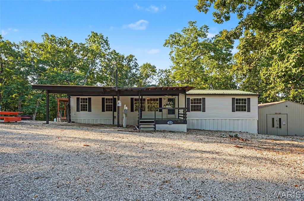 Live on vacation year-round! Enjoy the lakes, the side-by-side trails, the pool, the club house, campfires and friends! The tight knit & gated community of Woodland lakes is located just outside Sullivan and is home to many great amenities and activities! This particular home is located in a quiet more rural side of the community and offers 5 lots totaling nearly 2 acres.  Featuring a 24x40 shop, 3 detached carports measuring 18x20 and 3 covered decks, the idea of outdoor living, entertaining and storage is easy! Inside you are greeted by luxury vinyl plank flooring, cathedral ceilings, divided bedroom layout, open concept floor plan, a formal living and separate family room with woodburning fireplace, and a spacious kitchen and dining area that leads to the massive back deck. This is one you will want to see. With a little love, it could be the perfect weekend or full-time retreat. All appliances stay!