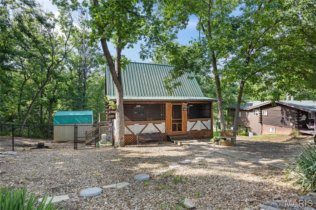 Escape to this adorable 2-bed, 2-bath rustic log cabin tucked away in the woods off Horseshoe Bend in Lake Ozark, MO! Perfect as a private retreat or a lucrative investment—short-term rentals are allowed! This property seamlessly blends rustic charm w/ an extensive list of modern upgrades. Enjoy the brand-new, enclosed 5x23 screened front porch or relax on the new oversized back deck overlooking a fully fenced backyard. Inside, you'll find new LVP flooring, beautiful hardwood floors, new solid wood interior doors, ceiling fans, & updated lighting. The fully remodeled upstairs bath & brand-new downstairs bathroom add immense convenience. The kitchen boasts new stainless-steel appliances, a gas stove, garbage disposal, & new faucets. Key improvements for total peace of mind: 2 mini-split systems, new windows & screens, new code-compliant septic system & new plumbing & Durable metal roof & a matching outdoor storage shed! Boasting plenty of open parking & an ideal location just minutes from premier shopping, dining, & entertainment, this gem won’t last long. Current tenant lease to end of year but owner will buy out lease! Schedule your tour today!