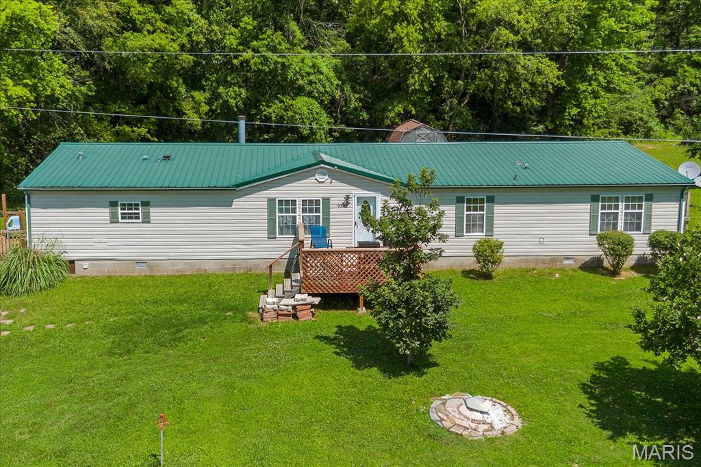 Wonderful property consisting of over 10 acres with outbuildings and a lake.  This sprawling property consists of a large 4 bed 2 bath manufactured home on a a block foundation, 2 pole barns (one with a side carport/porch), storage shed and lake.  The home is an open concept with a wood burning fireplace in the living room,  kitchen with breakfast bar, dining area, laundry room with extra space for another refrigerator or upright freezer, primary bedroom with two walk-in closets, primary bath with a soaking tub and separate shower, 3 additional bedrooms, full guest bath, and a large family room with built-in entertainment area.  The home has a front deck/porch and decks on both sides.  A 50 year metal roof was installed in 2019, new hvac installed in 2023, and new water heater in 2018.  The two pole barns are perfect for storing boat, camper and other sport utility vehicles.  Both barns have concrete floors and garage door openers.  You will find trails in the woods and plenty of space for gardening, pool, or more buildings if needed.  This is a great property with plenty of privacy, hunting, fishing, or for you to simply enjoy the quiet country life.  Great view of fields and wildlife.  All appliances stay, including washer and dryer. Buyers and buyer's agents to verify all information.