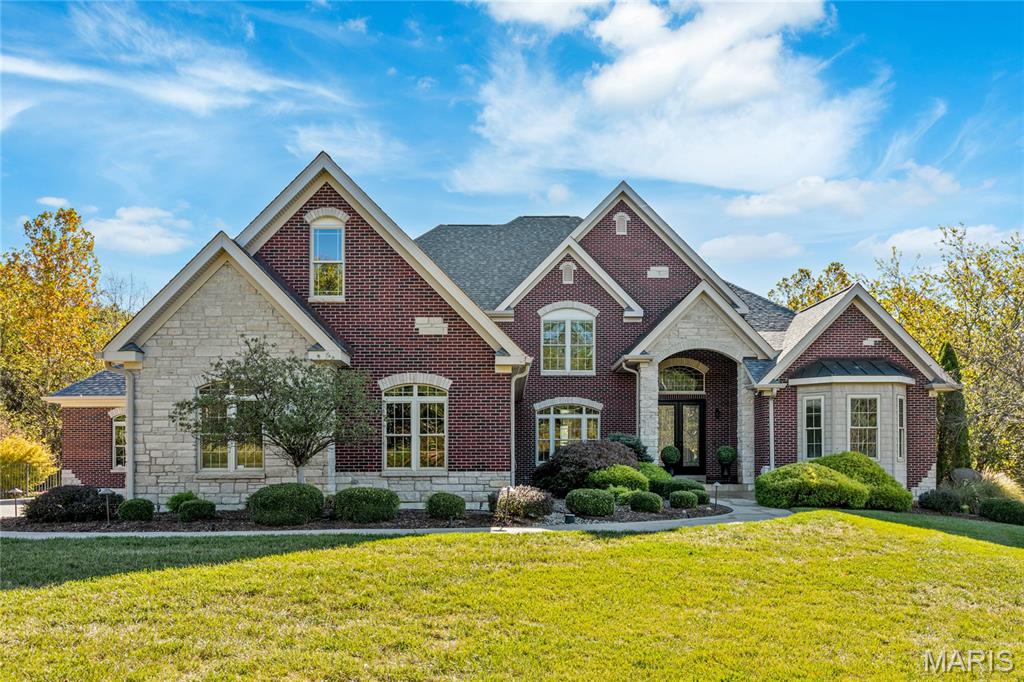 Spectacular brick & stone estate home on 3.5 acre grounds features best-in-class finishes and amenities throughout. Impressive front porch entrance with 8’ double wrought iron doors leads to 2-sty hardwood foyer, elegant dining room framed by wide scalloped entryways and stunning great room with stone fireplace flanked by 2-sty windows. Designer kitchen with 42'' buff cabinetry, granite countertops, professional grade stainless steel appliances & 8’ center island adjoins light-filled breakfast room that opens to terrace & outstanding hearth room with stone fireplace. Coffered primary bedroom suite with wide bay window & luxury bath with freestanding tub & shower spa plus a 2nd office / guest suite with full bath complete the main floor living quarters. Oak staircase accesses 3 additional bedrooms, 1 with ensuite bath & 2 with Jack n’ Jill bath plus large bonus room. Lower Level entertainment space includes recreation room, game room, fitness studio, 2nd kitchen & full bath. Atrium doors open to outdoor living area with covered patio, Baker free form resort style pool with grotto & waterfall plus flagstone patio with fire pit surrounded by landscaped gardens. Oversized three car garage with built-in storage cabinetry & service staircase to lower level. Award winning Francis Howell school district.