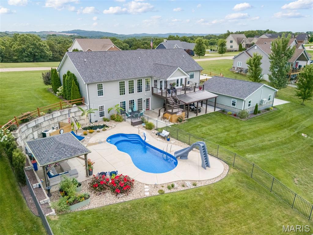 Welcome to the ultimate private estate—an extraordinary luxury atrium ranch situated on more than 2 beautifully landscaped acres. Completely transformed with exceptional attention to detail, this remarkable home offers 5 bedrooms, 4 full baths, and an impressive six-car garage.The backyard rivals a five-star resort with a 15x35 saltwater fiberglass in-ground pool, hot tub, gazebo, peaceful goldfish pond, palm trees, colorful landscaping, and expansive outdoor entertaining areas. Enjoy a stamped-concrete patio, covered patio, and large partially covered composite deck. Irrigation systems service both the front and backyard. The newer 30x30 “Garage Mahal” is a dream for car enthusiasts, hobbyists, or collectors, offering HVAC, epoxy flooring, and Trusscore wall panels. Inside, gleaming hardwood floors flow through the main living areas. The dramatic great room features a gas fireplace and coffered ceiling with tongue-and-groove wood inlays. The well-appointed kitchen includes a large center island, granite countertops, double ovens, gas cooktop, custom cabinetry, under-cabinet lighting, tile backsplash, and walk-in butler’s pantry. The luxurious primary suite offers a coffered ceiling, large walk-in closet, spa-like bath, and private access to the deck. The divided-bedroom floor plan provides additional privacy for family and guests.The finished lower level is ideal for entertaining or extended living, featuring a full second kitchen, built-in cabinetry, beverage cooler, recreation room with fireplace, guest bedroom, full bath, and dedicated workout room.Every detail of this one-of-a-kind estate was designed for luxurious everyday living, unforgettable gatherings, and resort-style relaxation. This is more than a home—it is a lifestyle.