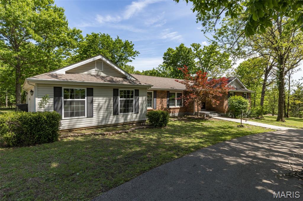 Welcome to this beautiful Lakewood home in Bonne Terre, offering the perfect blend of comfort and privacy on 1.76 acres! This 4-bedroom, 3 full bath home features an open-concept layout with a cozy wood-burning fireplace in the living room. The kitchen is a standout with custom cabinetry, breakfast bar, and stainless steel appliances including a double oven range with hood, refrigerator, and dishwasher.  The spacious master suite includes a walk-in closet and a private full bath. You’ll also appreciate the separate laundry room with water softener that leads to the attached 2-car garage. Step outside to a composite deck overlooking peaceful wooded surroundings—ideal for relaxing or entertaining.  Additional highlights include a circle drive, newer Andersen windows throughout, city sewer, and private well water. As an added bonus, all furnishings may stay, making this home truly move-in ready!
