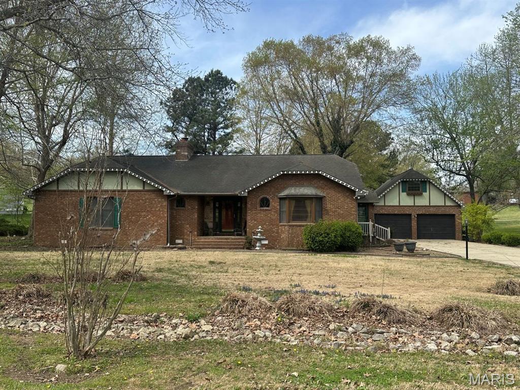 Charming cottage-style brick home set on 1.5 wooded acres at Hidden Trails Golf Course in Dexter, MO. Surrounded by nature, this one-owner home blends comfort and craftsmanship with beautiful brick detailing and a welcoming bay window. Inside, a cathedral-ceiling great room features a cozy fireplace and access to two primary suites, each with ensuite baths, soaking tub/shower & dressing areas. A shared walk-in closet & spacious laundry add convenience. A versatile den with French doors leads to the kitchen & dining areas. Enjoy the 8x20 sunroom with access from multiple rooms & views of stunning western sunsets from the deck. Detached garage includes guest quarters with living area, kitchenette, bedroom & bath. Geothermal HVAC adds efficiency. So close to the golf course & facilities of dining, swimming & enjoying time with friends & family & yet so close to 'home'! You have to see it! The home living area, sunroom & mud room total 2289 square feet for you to treasure and enjoy!