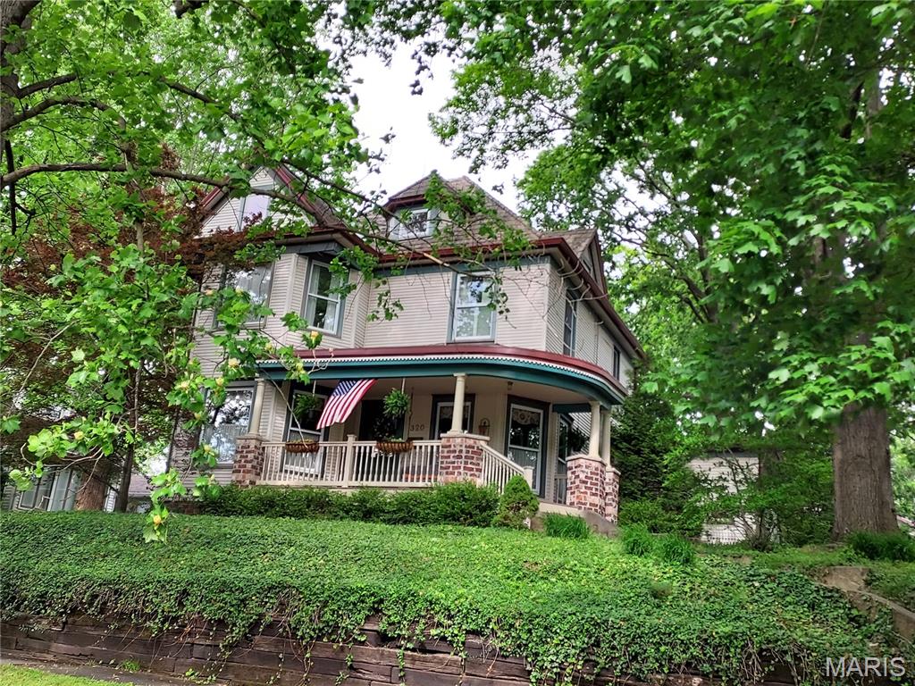 Perched high on an ivy-covered hill beneath towering shade trees, this stunning 4 bed, 3 bath turn-of-the-century Victorian is the perfect blend of timeless charm and modern comfort. Every update has been thoughtfully completed so you can enjoy all the character of a historic home without sacrificing today’s conveniences.

Inside, original hardwood floors and beautifully preserved woodwork, on all 3 levels of the home, showcase the craftsmanship of another era, while the fully updated kitchen features stainless steel appliances, modern finishes, and the functionality today’s buyers expect. Major improvements include updated wiring and plumbing, all vinyl replacement windows, and dual zoned efficient central air and forced air furnace. No bulky old radiators here!

Step outside and you can relax on the classic front porch swing or unwind on the shaded back patio surrounded by mature trees and peaceful views.  The property also includes an additional lot with a large open yard, perfect for entertaining, gardening, or simply enjoying the extra space, as well as an enormous 28 x 40 garage with room for vehicles, hobbies, storage, or a workshop.

This is more than a home—it’s everything you've dreamed of since you first saw "Meet Me in St. Louis". It's the Victorian dream, lovingly preserved and perfectly updated for modern living.