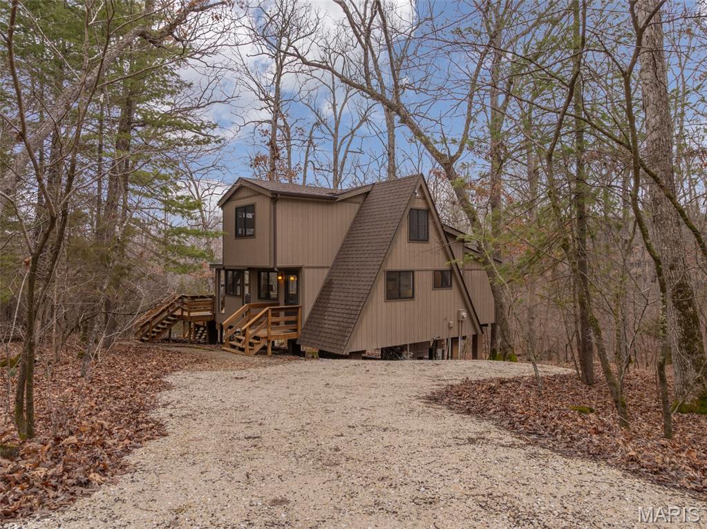 Summer is just around the corner and this lake front chalet at Innsbrook is ready and waiting for you. Clean, furnished, and truly move-in ready, this inviting getaway is tucked among the trees and surrounded by nature. Step inside and you’ll immediately notice the abundance of windows framing peaceful views of the woods and lake. The iconic A-frame living room is a showstopper, featuring three walls of glass that flood the space with natural light. On cool evenings, light the pellet stove and enjoy the warm, relaxing atmosphere that makes this chalet feel like a true retreat. The main level offers a spacious primary bedroom and full bath for easy living. The cute and bright kitchen is ready for meal prep. Upstairs, a generous sleeping loft includes two sets of bunk beds and two twin beds, providing plenty of room for family and guests.
Outside, two expansive decks offer incredible space to relax, grill, dine, and entertain. Whether you’re hosting friends or enjoying a quiet morning coffee, there’s room for everyone to spread out and unwind. Follow the path down to your private lakeside dock on Bliss Lake, where you can fish, paddleboard, or simply soak in the peaceful waterfront setting. This special property is being sold mostly furnished (with a few exclusions) and is designated as a second home only. It  cannot be used as a rental or primary residence. If you’ve been dreaming of your own place at Innsbrook, this delightful chalet is calling your name.
