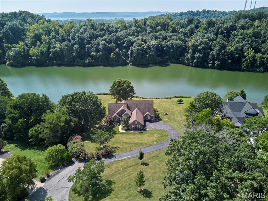 Welcome to your dream home in Augusta! This gorgeous custom-built lake house in the heart of Missouri's wine country is everything you've been waiting for! Nestled in the rolling hills just north of the Missouri River, this luxurious ranch in the Augusta Shores community features over 5,200 square feet of living space on 1.3 acres of picturesque property with direct access to the main lake in Augusta Shores, Hickory Lake. You'll have great curb appeal with a brick and stone exterior, oversized 3-car side-entry garage, and professional landscaping leading to the covered front porch. The foyer opens to the stunning 2-story living room, accented by columns and featuring a floor-to-ceiling stone-surround gas fireplace, hardwood floors, and a wall of windows to capture the amazing view of the lake. Off the living room is a charming sitting room with crown molding and 2-story windows. You'll love hosting gatherings in the gourmet kitchen, featuring granite counters, tile floors, beautiful cabinets with crown molding and glass-front accents, stainless steel appliances, and a tile backsplash. The light-filled breakfast room, breakfast bar, and expansive dining room provide plenty of space to eat, relax, and spend time with friends and family. No detail has been overlooked: archways, recessed lighting, chandeliers, wrought-iron spindles, art alcoves, and gleaming hardwood flooring. The primary suite is a retreat with vaulted ceilings, walk-in closet w/organizers, and a showstopper bathroom w/dual vanities, tile-surround step-in shower, and jet tub flanked by columns. You'll have three more bedrooms on the main level, each with their own en-suite bathroom and walk-in closet. A convenient laundry room w/utility sink and a half bath complete the space. The walk-out finished lower level adds a large rec room, kitchenette w/granite bar, family room w/gas fireplace, 5th bedroom w/walk-in closet, a bathroom w/step-in shower, and even a theater room! The thoughtful design of the interior continues outside. The giant ipe deck spans the back of the home, with unobstructed views of the lake and wooded hills surrounding you. You'll also have a covered patio, screened-in covered porch, and beautiful landscaping. In addition, the community amenities provide resident access to a pool, clubhouse w/exercise facility, tennis/pickleball courts, basketball courts, walking trails, pavilion, three stocked lakes, and fiber optic internet. Augusta Shores HOA fee includes gated security, pool and court maintenance, lake upkeep, snow removal, common ground upkeep, and internet service. The home is located moments away from Klondike Park and the Katy Trail, a short drive to the heart of Augusta and Defiance wine country, and only 25 minutes from shopping and restaurants in Washington or Weldon Spring. Don't miss out on this wonderful opportunity!
