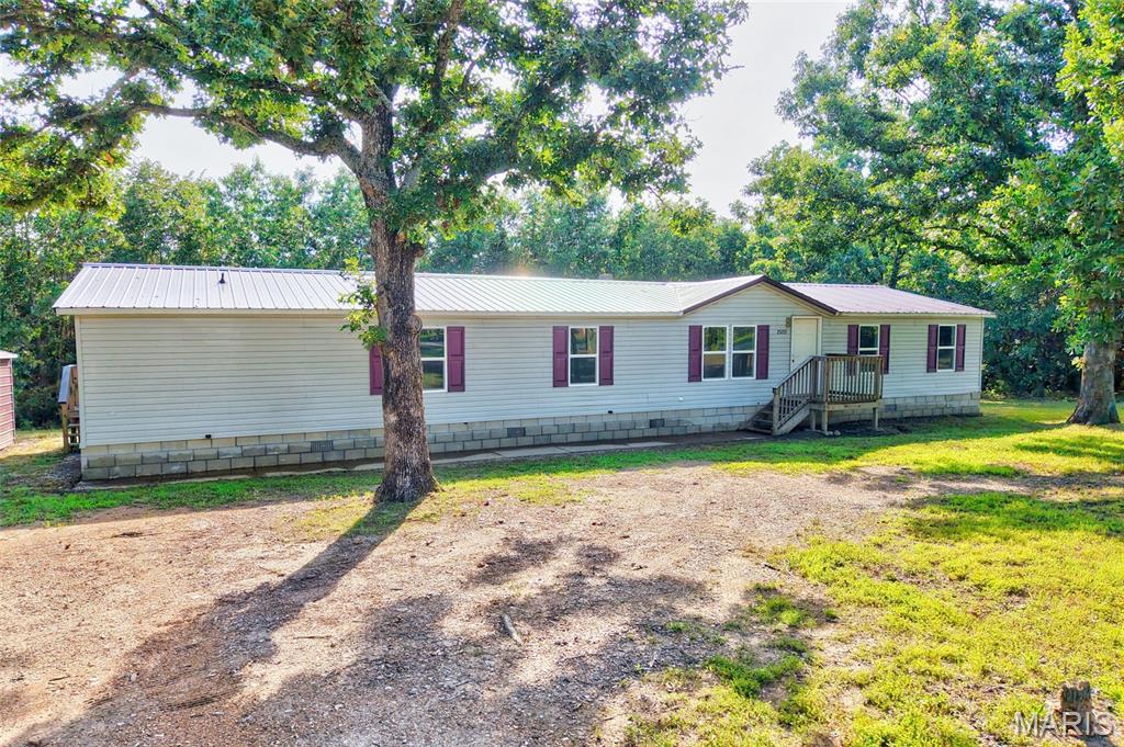 SPACIOUS 5 BEDROOM HOME ON 2+ACRES! Enjoy country living with the convenience of being just about 6 miles from town! Situated on 2.2 surveyed acres, this spacious home offers 5 bedrooms and 2 full bathrooms, about 2,200 sq ft of living space, providing plenty of room for family, guests, or a home office. This manufactured home is on a permanent foundation and features many upgrades, including newly installed luxury vinyl flooring throughout, fresh neutral, pale-color paint, and new stainless steel appliances! Then, outside, you'll find a carport with additional storage, along with plenty of open space to create a garden, explore your wooded backyard, or simply sit on your brand-new back deck and enjoy the quiet setting.  Located just minutes from shopping, dining, schools, and other local amenities, this property offers a blend of comfort & practical living space!