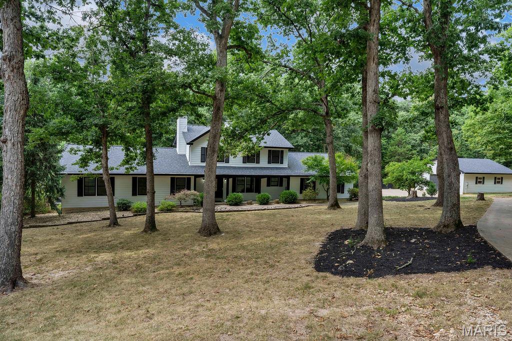 SPACE, ACREAGE & GARAGE GALORE! Nestled on just over 3 acres in desirable Defiance, this expansive 1.5-story home offers abundant living space, updates & the flexibility you've been looking for. The beautifully updated kitchen is a standout with white shaker cabinetry, solid-surface countertops, shiplap accents, pot-filler faucet, huge center island with built-in microwave drawer & breakfast bar, plus a walk-in pantry with cabinetry, shelving, electric & a wine cubby. Brazilian wood floors flow throughout much of the main level, while the vaulted great room features a wood-burning fireplace & stylish board & batten look accent wall. Step outside to the screened porch & expansive decking—perfect for enjoying the peaceful setting, sipping a delicious beverage or dining al fresco. The main-floor primary suite features a large walk-in closet & spacious bath with solid-surface counters, separate shower, oversized oval soaking tub & marble flooring. A beautiful library with built-in bookshelves & a separate private office provide wonderful work-from-home or quiet retreat options. Main-floor laundry includes cabinets, wash sink, closet & planning desk. Rounding out the main level is a convenient & updated half bath. Upstairs offers a loft bonus space, 3 generous bedrooms and a full bath. The finished walk-out lower level includes a large family room: perfect for binging favorite shows, game night or entertaining guests. And, a flexible bonus room would make a great study, workout or hobby space. Don't miss the half bath, large storage closet and BIG unfinished utility room. Recent improvements include Hardie Board siding (2022), TRIPLE-PANE windows (2024), FOUR  sliding doors (2024) & architectural roof (2021). THE GARAGE SPACE is truly exceptional: 3-car side-entry garage PLUS a 26x31 detached garage! Partial fencing is perfect for those with or wanting pets. NOT TO MISS: TWO furnaces & A/C systems AND A Wood-burning furnace * TWO water heaters—including one dedicated to the primary suite—add even more value. There is truly so much more! What a rare opportunity you must see for yourself!
