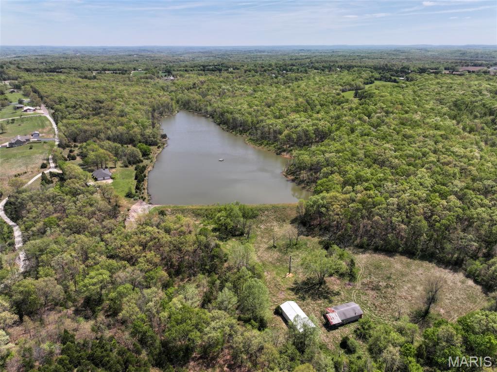 This 100.97 +/- acre property located just outside De Soto in Jefferson County, Missouri offers a mix of water features, timber, and existing improvements that support a variety of potential uses. The property includes a roughly 13 acre lake that serves as a central feature, providing opportunities for fishing, wildlife observation, and general recreation. The surrounding acreage consists largely of timber, creating habitat for local wildlife and offering privacy across much of the tract. Access to the property is provided by frontage along Yellow Rock Road on the northern boundary. An overgrown trail system runs through the southern portion of the property, which could be cleared and maintained to improve internal access for walking, ATV use, or land management activities. The layout of the property allows for navigation across different sections of the land with some improvements to existing paths. Improvements on the property include a large home that is in need of repairs and updates. The residence is configured with four bedrooms and three bathrooms and may serve as a primary residence, weekend retreat, or project for renovation. The property is being offered Selling As Is, and buyers should plan accordingly when evaluating the condition of the home and other improvements. In addition to the home, there are two older outbuildings that could be used for storage, equipment, or workshop space depending on their condition. The combination of timber, water, and open areas supports a range of uses such as hunting, fishing, and general outdoor recreation. The wooded portions provide cover and travel corridors for wildlife, while the lake adds a year round water source. These features contribute to the overall functionality of the land for outdoor activities and habitat management. This property is located approximately 5 miles from De Soto, providing access to groceries, fuel, and basic services. Hillsboro is approximately 15 miles away and offers additional amenities including shopping and dining St. Louis is roughly 45 miles to the north, offering access to a larger metropolitan area for employment, healthcare, and entertainment. Overall, this 100 acre tract in Jefferson County offers a combination of acreage, water, and existing structures. With road frontage, a sizable lake, and a mix of timber and improvements, the property provides a foundation for a range of uses.