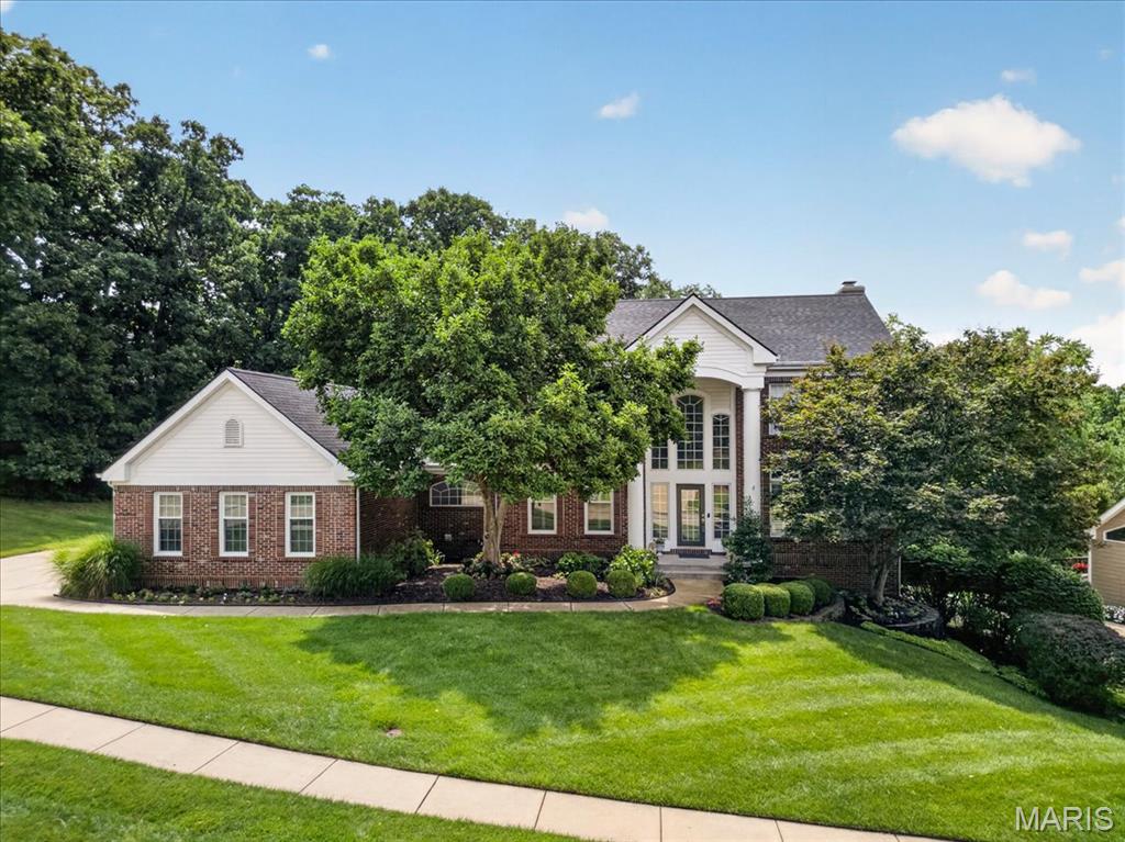 Nestled on a level lot backing to mature trees in the highly desirable Wildhorse subdivision, this beautifully maintained two-story home offers timeless style, exceptional updates, and an outstanding location just minutes from Chesterfield Valley's shopping, dining, and entertainment. Residents enjoy resort-style neighborhood amenities including pools, lakes, walking trails, sports courts, playgrounds, and more. A dramatic two-story foyer welcomes you inside, where rich hardwood flooring, crown molding, and abundant natural light set the tone throughout the main level. The spacious great room features a gas fireplace, built-in speakers, a bay window, and a door opening to the deck, and with the adjacent living/music room and a formal dining room, provides elegant yet comfortable spaces for entertaining or everyday living. The remodeled kitchen, architected and built by Karr-Bick, is designed to impress with custom 42-inch Mouser cabinetry, granite countertops, a center island, walk-in pantry, butler's pantry, and premium appliances including a Wolf 6-burner gas cooktop, Sub-Zero refrigerator and sub-zero wine cooler, and Whirlpool double ovens. The adjoining breakfast room features a dry bar with wine refrigerator and French doors leading to the deck, while the vaulted hearth room offers a second gas fireplace, built-in speakers, and oversized windows that fill the space with natural light. Upstairs, the spacious primary suite offers a coffered ceiling, dual closets, and a beautifully remodeled spa-like bath featuring Cambria countertops, dual vanities, a custom tile shower, jetted tub, and vaulted ceiling. Three additional bedrooms are served by two full baths, providing plenty of space for family and guests. The finished walk-out lower level expands the living space with a large rec room, family room, theater room with built-in speakers, private office, wet bar, full bath, and luxury vinyl plank flooring throughout. Outside, enjoy the private wooded backdrop from the spacious deck and beautifully maintained yard. Extensively updated over the years, this home reflects true pride of ownership with a remodeled kitchen and primary bath, updated flooring, newer Pella windows and patio door, LeafFilter gutter guards, zoned HVAC, a 2025 roof, and numerous additional improvements.