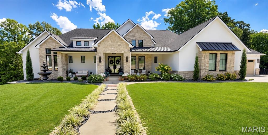 This is the kind of home that simply takes your breath away. From its stately exterior to its beautifully curated interior, every space feels polished, welcoming, and designed to impress. The incredible attention to detail is evident at every turn, and nothing was overlooked in creating a home that is as thoughtful as it is beautiful.

Step inside to soaring ceilings, dramatic beams, and a magnificent floor-to-ceiling stone fireplace anchoring the light-filled great room. Gorgeous white oak floors flow throughout the main level, bringing warmth and natural beauty to every space, while mostly Restoration Hardware lighting adds sculptural elegance and a soft, inviting glow. The adjoining kitchen is a true showpiece, featuring custom white oak cabinetry, a massive island dressed in quartz, Sub-Zero and Wolf appliances, and an effortless flow made for gathering.

The serene primary suite feels like a private retreat, complete with a spa-inspired bath featuring a waterfall and jetted tiled shower alongside a picturesque soaking tub. Handsome and refined, the adjacent moody study provides the perfect complement. Even the secondary bathrooms reflect the home’s exceptional level of craftsmanship, with custom cabinetry and beautifully tiled showers.

Walls of windows frame peaceful views, while the outdoor living spaces are every bit as extraordinary as the interior. Dine beneath the wood-lined vaulted porch, overlooking the pond and mature tree canopy… a setting made for colorful dinner parties, weekend brunches, and lingering fall evenings. Just around the corner, a second covered porch becomes a cozy open-air living room centered around a striking, stone, see-through fireplace. Whether you’re cheering on your favorite team, curling up by the fire, or simply soaking in the view, these porches make every day feel like a getaway.

And just when you think you’ve seen it all, the lower level raises the bar- literally! Enjoy a stunning marble-clad built-in bar, spacious fireside family room, whimsical playroom, private home gym, and an incredible golf simulator and theater area.

Sophisticated yet comfortable, grand yet incredibly livable, this extraordinary home proves that thoughtful design and luxury can be found in every last detail.