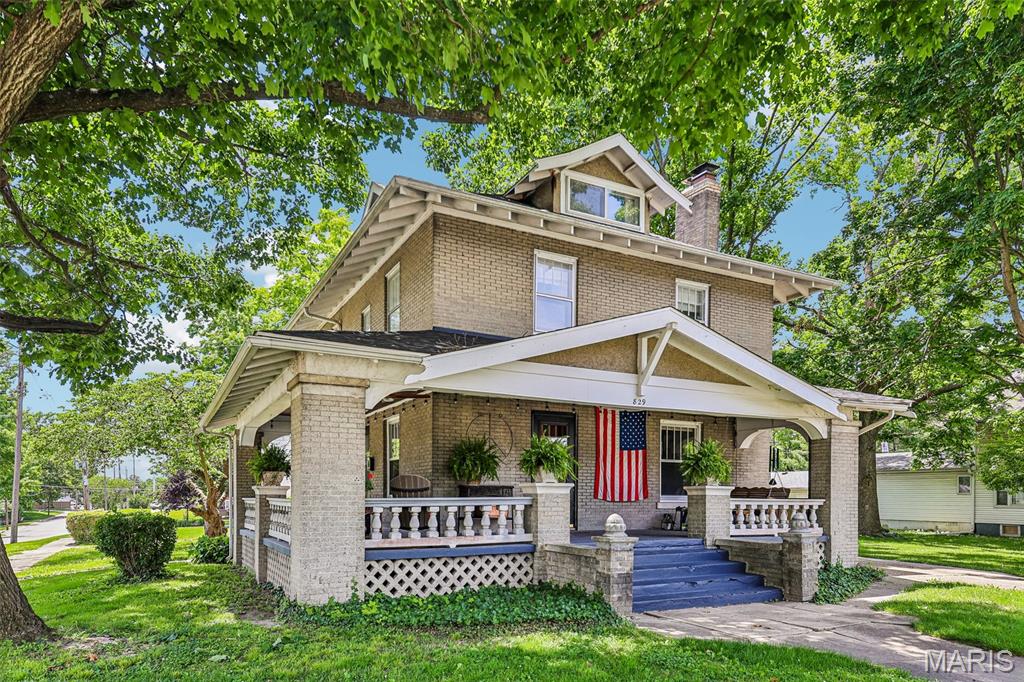Step into timeless character and craftsmanship in this beautifully maintained 1920 brick Craftsman home where the integrity of the era has been lovingly preserved. From the moment you arrive, you’ll appreciate the concrete drive extending from the front entrance around to the rear garages, offering exceptional convenience with a 3-car detached garage plus an additional separate storage garage. The welcoming wrap-around covered concrete porch showcases the original mahogany ceiling and stunning acorn finials, setting the tone for the remarkable details found throughout the home.

Inside, you’ll find all original interior and exterior doors, gorgeous original wood flooring, and an impressive wood staircase leading to the second floor. The living room features a brick wood-burning fireplace flanked by custom-built glass door bookcases with beautiful leaded windows above. Large windows throughout the home flood every room with natural light while highlighting the incredible craftsmanship and warmth of the space. The formal dining room offers a built-in hutch perfect for entertaining and displaying treasured pieces.

The quaint kitchen embraces its original utilitarian design where every element serves a practical purpose, while the charming breakfast nook surrounded by windows creates the perfect spot for morning coffee. On the 2nd floor you’ll find 2, possibly 4 more bedrooms, each filled with unique character including window seats, walk-in closets, and built-ins designed for both comfort and charm. One of the home’s most special features is the treehouse-like sleeping porch, creating the ultimate staycation retreat. The bathroom showcases classic penny round mosaic flooring, true to the era of the home.

The heated and cooled “Crow’s Nest” attic space offers endless possibilities as a bedroom, an office, teen retreat, man cave, studio, or private getaway. Additional updates include a new boiler in 2024, new roof in 2025, all new main floor lighting, and new toilets on the main floor and basement. Conveniently located on a extra large lot, near hospital, downtown shopping, restaurants, entertainment, schools, and even a bus stop directly out front, this one-of-a-kind Craftsman is truly a rare opportunity to own a piece of history. Call today and book your appointment!
