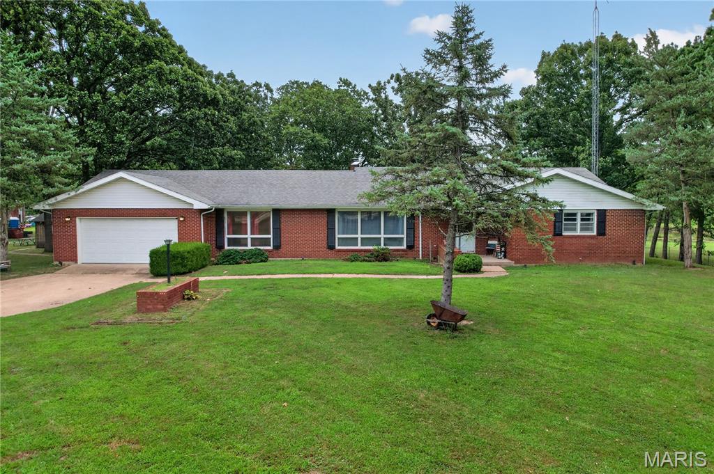 Welcome home to this beautiful brick residence nestled on approximately 1± acre just outside of Waynesville, Missouri. Surrounded by mature shade trees and peaceful countryside views, this well-maintained property offers the perfect balance of comfort and space. Step inside through the welcoming entry foyer and discover a thoughtfully designed floor plan featuring 3 spacious bedrooms, 3 full bathrooms, a dedicated office, formal living room, and a warm, inviting family room/den complete with a wood-burning fireplace and striking beamed ceiling. The spacious kitchen offers an abundance of cabinetry for storage and workspace and flows into a separate dining room, making it ideal for family meals and entertaining. A convenient main-floor laundry room adds to the home's functionality. The generous primary suite is located on the main level and features ample closet space along with a private en-suite bathroom, creating a comfortable retreat at the end of the day. The full unfinished walk-out basement provides endless possibilities for additional living space, storage, or a workshop, with direct access to a covered patio. Relax on the back deck while enjoying scenic views overlooking the field and pond, or spend your evenings beneath the beautiful mature shade trees that frame the property. An additional outbuilding offers extra storage for equipment, hobbies, or lawn and garden tools. If you're looking for peaceful country living with the convenience of being just minutes from Waynesville, this property is one you won't want to miss!