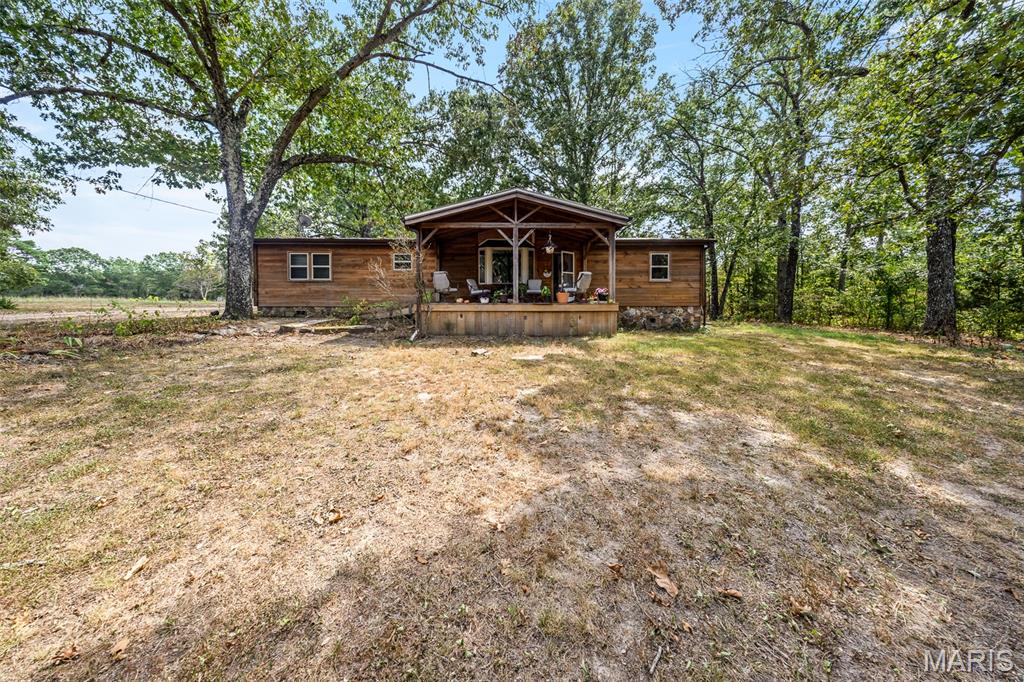 Escape to the country and enjoy the peace and privacy of 34 acres m/l! Tucked away at the end of a long, winding driveway, this rustic property offers the seclusion you've been looking for, with a creek winding through the land and abundant wildlife all around. The 3-bedroom, 2-bathroom home features wood siding, a durable metal roof, and beautiful timber-frame covered front and back porches that invite you to slow down and enjoy the quiet surroundings. Inside, the open-concept living, kitchen, and dining areas provide a comfortable gathering space with plenty of opportunity to add your own personal touches. The primary suite offers a full bathroom with shower, while two additional bedrooms, a full guest bathroom, and laundry room complete the home. The home has forced air propane heating with an outdoor wood furnace for back up on those chilly winter nights. The property offers plenty of room for all your country-living adventures, with garden space, woods to explore, wildlife to watch, and a creek to enjoy. The oversized detached 2-car garage provides excellent space for vehicles, equipment, projects, or hobbies, while the barn with lean-to adds even more storage and versatility. Whether you're looking for a private homestead, a weekend retreat, a place to garden and explore, or simply a quiet piece of land away from the hustle and bustle, this 34-acre property is full of possibilities. Bring your vision, add your finishing touches, and make this peaceful slice of the country your own!