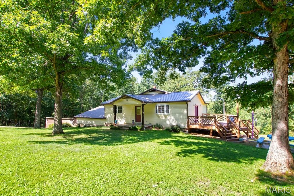 Escape to the peace and privacy of country living with this spacious ranch home on 14.83 acres, tucked away on a private road just outside of town. Offering 4 bedrooms and 3.5 bathrooms, this home features an open concept layout with generous living spaces, walk-in closets, and plenty of room for family and entertaining. The spacious primary suite includes a walk-in closet and a private spa room, creating the perfect retreat. A unique feature of this home is that both the main level and lower level offer their own kitchen, dining, and living room areas, making it ideal for multigenerational living, guests, or hosting gatherings.
Step outside to enjoy the large side deck overlooking the beautiful property, where you’ll find abundant wildlife, open yard space, heavy duty playground, and a welcoming outdoor gathering area. The oversized 3 car attached garage, nearby woodshed, and separate workshop provide plenty of storage and room for hobbies, especially woodworking enthusiasts.  The walkout lower level is highlighted by a beautiful stone wall and tile hearth with a cozy wood stove, adding warmth and character. With a little updating, this property offers incredible potential to create your dream country home while enjoying privacy, acreage, and a convenient location just minutes from town.  Schedule your showing today!