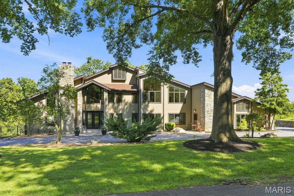 Amazing opportunity to own this one of a kind, stunning home with 6712 sq. ft. of living space and over 3 acres in a spectacular Chesterfield location, cul-de-sac and backing to woods.  Features include soaring ceilings in the entry, living room, dining room, primary suite and primary bath.  Walls of windows flood the home with natural light. The custom chefs kitchen with Viking Professional appliances, 8 1/2 foot movable island. Open flow to the hearth room with built-in shelving and a fireplace, perfect for gathering with family and friends.  Off the kitchen a brand new composite deck with soffits and guttering.  The main floor has two bedrooms with custom closets. The main floor full bathroom with luxurious walk-in shower featuring  both a rainfall showerhead and a convenient handheld shower wand.  Laundry room on the main level.  Living room, family room and half bath also on the main level.  Upstairs the primary suite is pure luxury with gas fireplace, sitting area, deck to have your morning coffee and watch the sunrise.  The primary bath with soaring ceilings, lots of natural light, walk-in shower, separate jetted tub, 9 1/2 ft. double vanity.  Next bedroom on 2nd floor has custom closets and it's own new composite deck with soffits and guttering, overlooking the pool.  The bath has a NEW beautiful walk-in shower with incredible rainfall showerhead and a handheld wand as well, an adult height double vanity. Third floor has a bedroom/bonus room with built-in shelving, sitting area and a large window that over looks the back yard. This home has a total of 5 fireplaces. New closet systems. Large finished walkout lower level with family room, rec room w/bath that would work well as in-law quarters. Inviting exercise room featuring a wall of windows overlooking the beautifully landscaped backyard, bringing in an abundance of natural light.  Full bath with walk-in shower.  Sunroom, that is perfect for hosting pool parties.  Gunite saltwater pool with automatic pool cover.  Fenced yard, perfect for your pet, inground sprinkler system, circle drive, side entry 4 car garage with new polyaspartic flooring.  Elevator, ADA features, home security system and ring camera systems. Ultraviolet Air System, Custom windows and doors. Art pieces commissioned by local artist, Brother Melvin Meyer in three separate locations throughout the house.
This is a truly MUST SEE custom estate you won't want to miss.