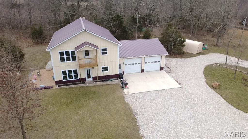 New Price! Located just 4 miles from town on a chip-and-seal road, this 2022-built home offers 2,160 sq. ft. of living space with 5 bedrooms and 2 bathrooms. Situated on 6.69 level acres, the property provides plenty of room for horses, livestock, chickens, or your ideal homestead setup. Established garden areas with raised beds are ready for summer planting, and a small pond adds to the charm of the property. The land also features 4 peach trees, 2 apple trees, and 1 cherry tree, along with black and red raspberries, a blueberry cane, and a peppermint tea bush—perfect for those looking to enjoy homegrown produce. The home features a durable metal exterior and metal roof, 2-car garage, and a separate storage building.. A circle white chat driveway provides easy access. Inside you'll find a spacious kitchen with abundant custom handcrafted cabinets and stainless range, refrigerator, dishwasher, and microwave. The main level includes a comfortable living room, laundry area with washer and dryer included, and a large master bedroom. Upstairs offers four additional bedrooms and a separate family room. Equipped with multiple high-efficiency mini-split systems for heating and cooling, plus a wood pellet stove for supplemental heat. Average utility costs are approximately $200 per month. Located in the Green Forest R-2 School District, this property blends modern construction with peaceful country living. Schedule a private showing today!