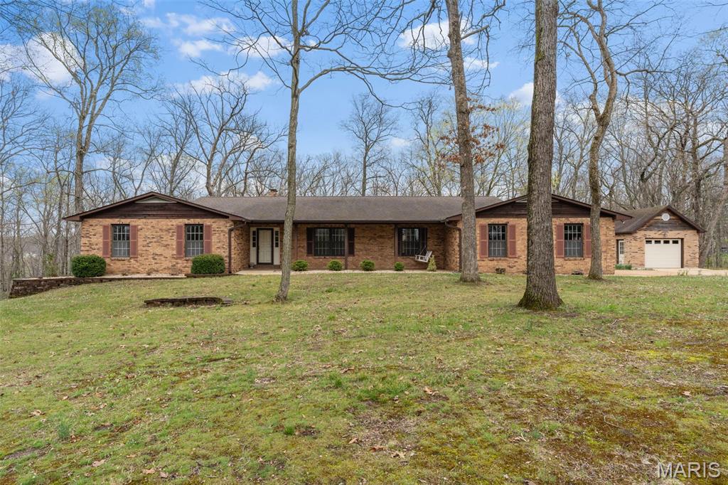 Original Owner! This solid, well maintained 1978-built ranch home has vintage charm and is nestled on 3.15+/- scenic acres, full of charm, space and timeless character. A large entry welcomes you into a cozy great room featuring a classic wood-burning fireplace, wood ceiling, and highlighting with exposed beam accents. The kitchen offers a functional layout with stainless steel appliances, backsplash, breakfast bar, and a bright breakfast nook with bay windows. A separate dining room and a sunken living room. The primary bedroom suite offers a walk-in tile shower, 2 closets, and a high vanity sink, also a private access to a large composite deck, creating a relaxing retreat. The home includes 2 additional bedrooms, a full hallway bathroom and a convenient main floor laundry room adjoining to a half bath. The beautiful wood floors adds warmth throughout some of the main level. The lower level features a partially finished basement with a spacious rec/family room, a second wood-burning fireplace, and walk-out access to a sizable patio, idea for gatherings or quiet evenings. Outdoor space truly shines with a large composite deck across the back of the home, a screened-in porch, and a peaceful, park-like setting. the property includes an oversized two-car attached garage and 1 car detached garage, offering plenty of room for vehicles, hobbies or storage. This property is being Sold in Current Condition "Sold As Is" Seller to do no repairs. Restrictions, HOA $300 a year, Special Assessment $300 a year. Easy to show, call today to set up your appointment.
