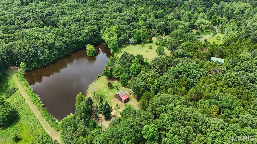 Just over an hour from downtown St. Louis, discover an extraordinary opportunity to own your own private family retreat, recreational getaway, or legacy property! Offering an exceptional combination of comfort, recreation, and functionality, this one-of-a-kind estate is designed for making memories that will last for generations. At the heart of the property is a beautifully restored log cabin, thoughtfully renovated while preserving its rustic character. Featuring hardwood floors, a wood-burning stove, kitchen, full bath, and bedroom, it's the perfect place to unwind after a day spent outdoors. The impressive family hall (lodge) was built for bringing people together. Complete with a spacious gathering room, full kitchen, and full bath, it's ideal for family reunions, holidays, retreats, celebrations, or hosting large groups. Also included is an earth contact home featuring a kitchen with a Quartz island, wood-burning stove, dining area, three bedrooms, two baths, an attached garage, and workshop area. While the home is ready for updating, it provides an excellent opportunity to renovate into a comfortable full-time residence or guest home. The property's additional improvements include a 30x40 detached outbuilding with 2 garage doors, concrete floors, electric, and shelving, a charming greenhouse perfect for the master gardener, and a barn offering additional storage for equipment, tractors, ATVs, or recreational gear. Step outside and experience everything this remarkable property has to offer. Trails throughout the property invite peaceful walks, or ATV adventures. Spend your afternoons fishing in the beautiful, stocked lake or simply taking in the tranquil views and 2 additional ponds. An extensive irrigation system supplied directly from the lake supports the landscape and adds tremendous value to the property. Whether you're dreaming of a private family retreat, hunting and recreational property, hobby farm, or peaceful country escape, this exceptional estate offers endless possibilities in a convenient location just a short drive from St. Louis. Properties that offer this level of versatility, privacy, and recreation rarely become available. Come experience everything this incredible property has to offer! Showings begin Friday, July 10th at 9:00 a.m.