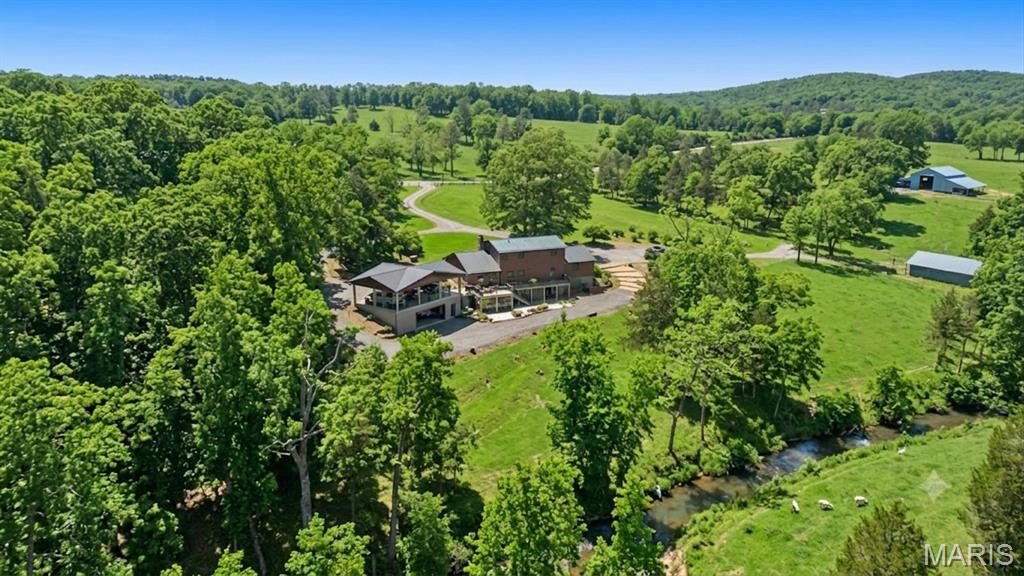 Welcome to your private dream escape! This exceptional 5-bedroom, 3.5-bath home is perfectly situated on 15.21 scenic acres and features approximately 900 feet of year-round, spring-fed Fourche Renault Creek frontage. Set in a very private setting, this property offers peace, seclusion, and plenty of room to unwind.
A remote-controlled gated entrance with security cameras provides added privacy and peace of mind. The property also includes a 950 sq ft heated workshop located under the carport, featuring 9-foot ceilings, a concrete floor, and an impressive 18-foot glass garage door overlooking the creek—an ideal space for hobbies, storage, or a creative workspace. Just outside, an outdoor sitting area overlooking the creek offers the perfect spot to relax and take in the views and sounds of nature.Whether you’re searching for a full-time residence or the ultimate weekend retreat, this property delivers. With high-speed internet available, working from home is convenient while still enjoying a quiet, natural environment. The expansive acreage provides endless opportunities for recreation, relaxation, and outdoor enjoyment.
Located just a short drive from Mark Twain National Forest and YMCA Trout Lodge, and only about one hour from St. Louis, this property offers the perfect balance of convenience and escape. Huzzah Valley Resort and Bass River Resort are also very close by, offering some of the area’s best canoeing and tubing.
With stunning creek frontage, modern connectivity, enhanced security, versatile workshop space, and an unbeatable location, this Washington County property truly offers the best of both worlds. Opportunities like this don’t come around often—schedule your showing today!