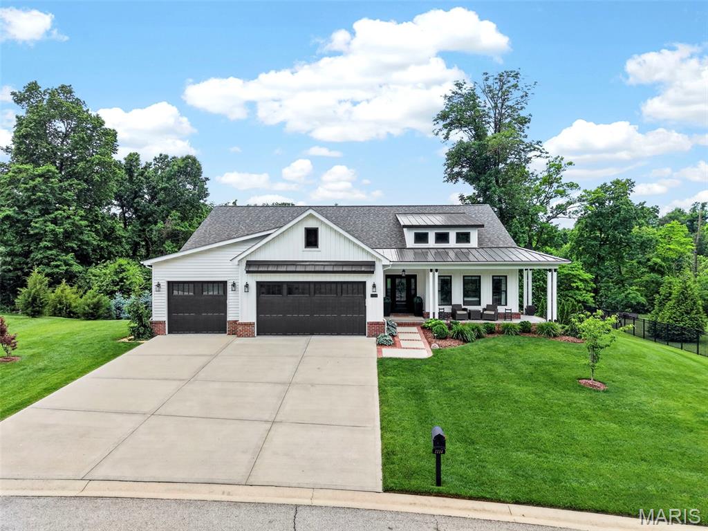 This breathtaking ranch home impresses from the moment you arrive. The Rain Bird irrigation system keeps the gorgeous landscaping easy to maintain, while the covered front porch wraps around the side of the home, creating the perfect place to relax with your morning coffee. Tucked away on a street that feels secluded, you still remain just a short drive from everything the Metro East and the Greater St. Louis area have to offer. Step inside to discover soaring 11-foot ceilings through the great room, with 9-foot ceilings throughout the rest of the main level and basement. Uniform luxury vinyl plank flooring flows throughout the main floor, creating a clean and cohesive feel. Built in 2021, the home is fresh and modern throughout. Just off the entry is the first bedroom complete with an enhanced custom closet. The spacious living room features a gas fireplace and expansive windows that fill the home with natural light. It opens seamlessly into the stunning kitchen featuring quartz countertops, custom Amish cabinetry, stainless steel appliances (including a professional grade Thermador range), a walk-in pantry, and ample counter space. Adjacent to the kitchen is the large dining area with direct access to the back deck, which also includes a gas hookup for grilling and a serene view of the backyard. The primary suite offers plenty of space along with a walk-in closet and a beautifully designed bathroom featuring a double vanity, rainfall shower with a second showerhead, and a built-in heater for added comfort. The third bedroom sits near the primary suite and main floor laundry room, which conveniently connects to the oversized three-car garage. The open walkout basement offers exceptional additional living and entertaining space, complete with a large kitchenette, third full bathroom with built-in heater, fourth bedroom, and an additional bonus room. The utility room provides extensive storage and could also function as an added workshop. Outside, the covered back patio overlooks a tree-lined backyard that feels private and tucked away. Between the high-end finishes, expansive living spaces, and pristine landscaping, this home is truly one you have to experience in person! Schedule your showing today!