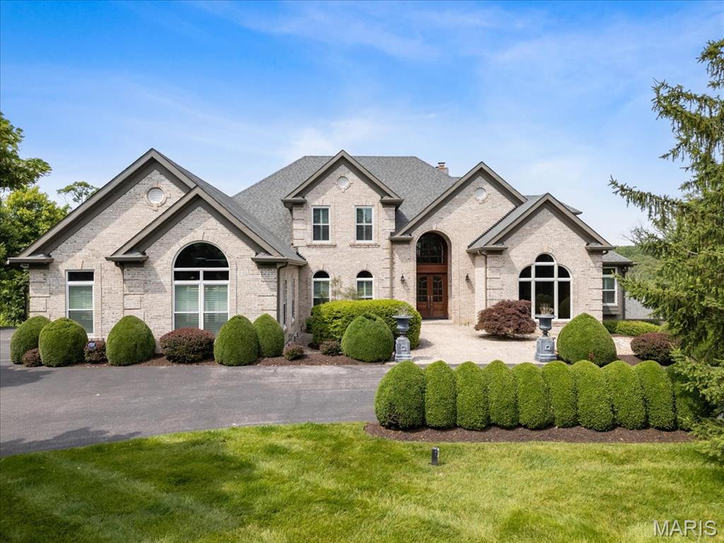 Absolutely breathtaking! This estately 1.5-story home is perfectly nestled on 8 acres of stunning, picturesque land. Meticulously updated throughout, it offers high-end finishes and exceptional attention to detail. The main level showcases rich hardwood flooring, a dramatic two-story foyer with a curved staircase, an elegant dining room, and a private study with custom built-ins. The soaring great room is filled with natural light from floor-to-ceiling windows and features a cozy gas fireplace and a stylish walk-behind wet bar—ideal for entertaining. The kitchen is a true standout with quartz countertops, stainless steel appliances, and seamless flow into the breakfast area, hearth room with stone fireplace, and access to the expansive deck. Retreat to the luxurious main-floor master suite, complete with a beverage bar and see-through fireplace leading into the spa-like master bath, which includes dual bathrooms and custom his & hers closets. The walkout lower level is an entertainer’s dream—boasting a full kitchen, wine cellar, second wet bar, family room, guest bedroom, full bath, rec/exercise room, and second laundry. A finished 4-car garage offers private access to the lower level, complemented by a circle drive, multiple patios, a deck and so much more.