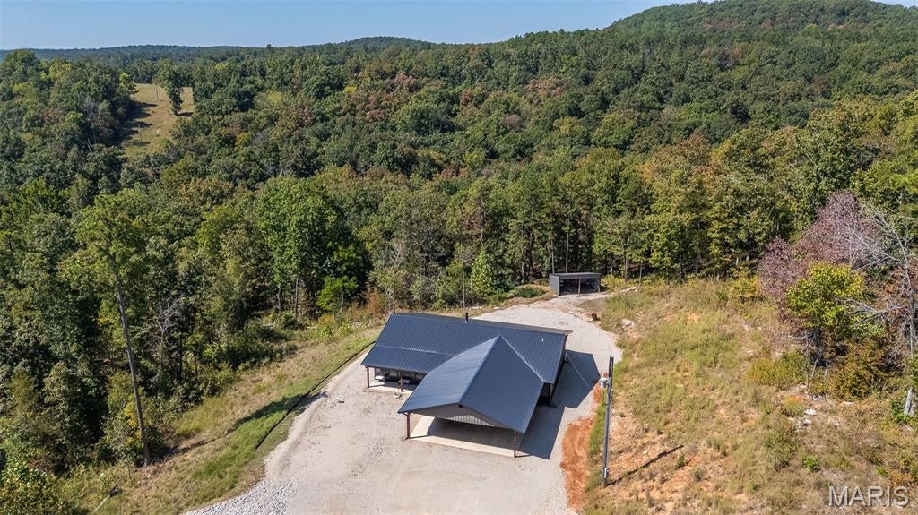 This contemporary home was built in 2021 and has architecture and design styles that reflect present day trends with metal siding and roofing for very low maintenance. Plenty of covered parking for 3 vehicles with a 12' x 9' storage building on it and wired for 220. Step inside into a large great room with custom cabinets and granite counter tops, a pantry and stainless appliances. There is a very nice woodstove for cool winter nights. This home sits on 6 acres with a great view and joins Pioneer Forest, which joins thousands of acres of Ozark National Forest.  It  is very close to the Current River for boating , tubing and fishing! Sit out on your huge 50' wide covered patio, ideal for peaceful mornings or entertaining. This home combines quality and craftsmanship.