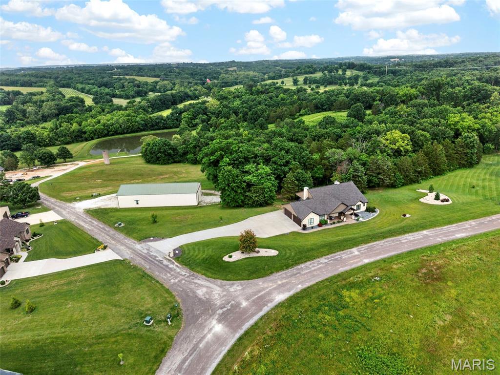 Experience luxury living at its finest in this exceptional custom ranch estate nestled on 3.48± acres of wooded privacy. Offering over 4,000 square feet of thoughtfully designed living space, this stunning home features 3 bedrooms, 3 full baths, and 2 half baths with upscale finishes throughout. A dramatic great room showcases soaring 14-foot ceilings, while 10-foot ceilings and 8-foot doors span the main level, creating an open and elegant atmosphere. The luxurious primary suite is a true retreat, complete with two expansive walk-in closets, a spa-inspired bath with separate vanities and a double-headed walk-in shower, plus private access to a screened-in deck overlooking the serene, wooded backdrop. The gourmet kitchen is designed for both everyday living and entertaining, featuring custom maple cabinetry, solid surface countertops, an oversized center island, and a custom walk-in pantry. Two impressive floor-to-ceiling stone wood-burning fireplaces, built-in bookshelves, crown molding, and exquisite craftsmanship throughout add warmth and character. The finished lower level is an entertainer’s dream, offering expansive gathering spaces, a custom wet bar, and dedicated wine cellar area. Additional features include energy-efficient geothermal HVAC and an extraordinary 50’ x 100’ outbuilding with 16-foot overhead doors and separate 400-amp electrical service. Whether you need space for boats, RVs, trailers, and recreational vehicles, or envision the ultimate party barn, sports court, pickleball facility, golf simulator, or hobby workshop, the possibilities are endless. A rare opportunity to own a private luxury retreat with unmatched amenities and versatility.