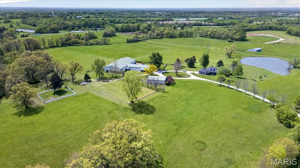 This is a one-of-a-kind EQUESTRIAN PROPERTY on private 38.11+/- acre LEVEL/GENTLY ROLLING lot in Elsberry with a CHARMING CUSTOM RANCH HOME W/2-CAR ATTACHED GARAGE, EXQUISITE BARN W/6 STALLS, INDOOR RIDING ARENA, RV/HORSE TRAILER CARPORT, OUT BUILDING, OUTDOOR RIDING ARENA, FENCED PASTURES, HIGH YIELD HAY FIELDS & a STOCKED POND! 3,266+/- SqFt, 3 bedroom, 3 full bath home. Quaint covered front porch greets you as you step inside the entry foyer. Spacious living room boasts a wood flooring, brick wood burning fireplace w/raised hearth, built-in custom bookcases, 13’+/- vaulted ceiling, walk-out to deck & wall of windows w/plantation shutters allowing plenty of natural light. Open, eat-in kitchen with custom cabinetry, Cambria Quartz countertops, tile backsplash, breakfast area & NEW Samsung Bespoke refrigerator w/pull-out freezer. Primary suite features recessed lighting, carpet, sitting area overlooking the beautiful/peaceful sprawling backyard & pond, walk-out to deck, & bath boasting double sink vanity w/Cambria Quartz, shower, jet tub & large walk-in closet. Two additional bedrooms feature spacious closets, carpet & share hall full bath. Laundry room & dining room completes the main level. Walk-out, lower level extends living quarters that flaunts a large rec room, office, exercise room, bonus room, full bath & large storage room for an abundant amount of storage. Within the Elsberry School District & easy access (4.5 miles) to HWY 61 (future I-64). SCHEDULE YOUR SHOWING TODAY!