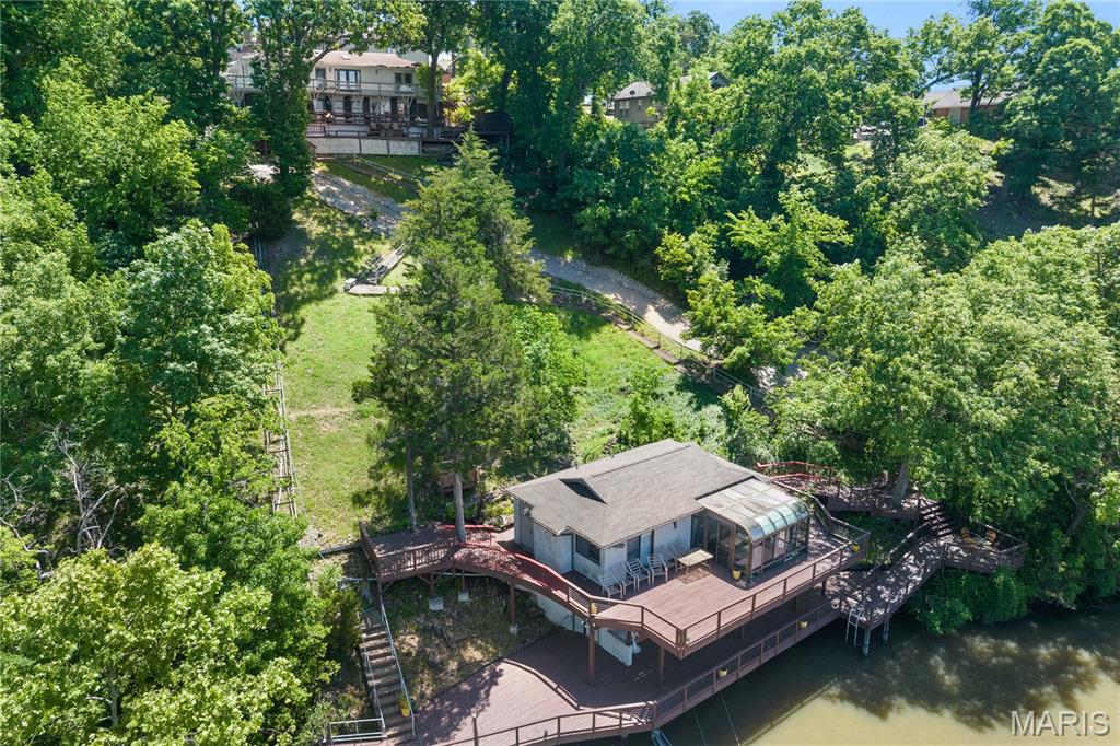 Don’t miss this incredible lakefront opportunity featuring a 5BD/4BA main home plus a 1BD/1BA guest house perched over the water on MM 17 in Lake Ozark! Offering big water views, a prime location by land and water, and nightly rental approval, this property is ideal for full-time living, multigenerational use, or investment. The one-of-a-kind guest house offers a large lakeside sunroom, full kitchen, living room, spacious bedroom, full bath, and extensive wraparound decking. Enjoy a newer 2-well concrete dock (12x36 + PWC slip) with a swim platform and storage/bar room with electric. The main home features two full kitchens (including a newly remodeled main kitchen), two living areas, two primary suites, two dining spaces, and a 2-car garage. Additional highlights include two wood-burning fireplaces, indoor/outdoor speakers, abundant decking (recently repaired and resealed), vaulted ceilings, newer roof and stucco on the guest house, flat driveway, main level living, and approx. 30’ of water depth. A new cart path to the dock adds easy access. Truly exceptional lakefront living—turn-key and ready to enjoy!