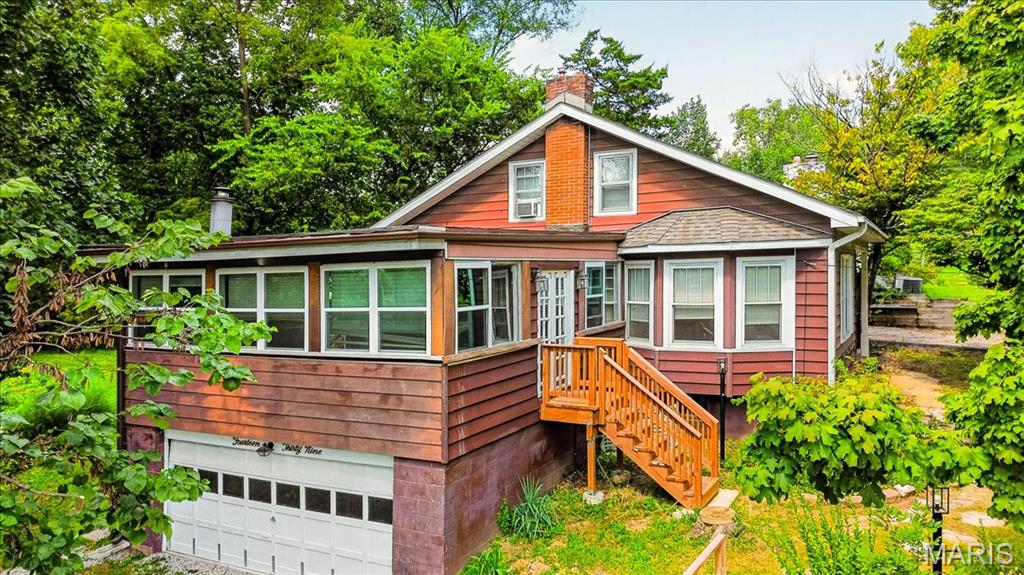 Est. 1923 — A Truly Rare Webster Groves Property! Tucked away on an exceptionally large, private property spanning two parcels and nearly an acre, this charming 1.5-story home offers something increasingly hard to find in Webster Groves—space, privacy, mature trees, and room to enjoy the outdoors without sacrificing a convenient location. The expansive lot creates a peaceful, tucked-away setting and provides an incredible amount of usable outdoor space, all within one of the area's most desirable communities. A cozy wood-burning fireplace in the 3-season room creates the perfect spot to enjoy crisp fall evenings while taking in the surrounding natural setting with its own private stair entry & exit. Inside, spacious living features beautiful wood floors and large windows that bring in an abundance of natural light. The kitchen offers a walk-in pantry with built-in cabinetry, providing excellent storage. The main level includes 2 bedrooms and full bath, while the upper level features two additional bedrooms and another full bath. An attached tuck-under 2-car garage offers convenient access to the walk-out lower level. Adding to the property's unique appeal is a dedicated greenhouse equipped with water, gas, and electric—a wonderful opportunity for gardening enthusiasts, hobbyists, artists, or anyone looking for a special space to create and enjoy year-round. The two-parcel configuration and expansive lot are a standout feature of this property. Whether you're looking for room to garden, entertain, play, relax, explore, or simply enjoy the privacy of a larger-than-typical Webster Groves property, this setting offers possibilities that are rarely available in the area. The mature trees and generous grounds create a peaceful retreat while still being close to everything Webster Groves has to offer. Updates include vinyl thermal windows, updated plumbing and electrical, a newer roof, newer furnace, central air, and sump pump.Ideally located just minutes from the shopping and dining along Big Bend Boulevard and Watson Road, with quick access to I-44 and within the acclaimed Webster Groves School District.A rare opportunity to own an expansive two-parcel property with nearly an acre of land in Webster Groves—offering the privacy and space of a much larger estate while remaining close to shopping, dining, schools, and everyday conveniences.