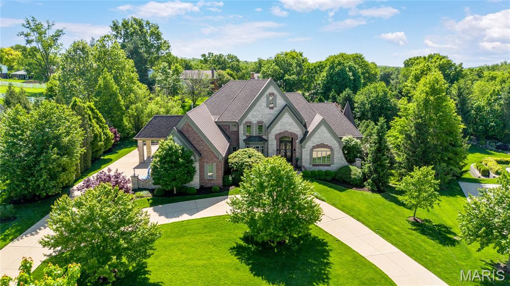 Situated in a gated enclave of custom-built homes, this exquisite 8,274 sq ft full brick and stone estate by W J Byrne seamlessly blends timeless architecture with modern luxury—further elevated by an exquisite remodel by K-Build Design. A striking barrel-vaulted porch with impressive 9-foot wrought iron double doors opens to a grand two-story foyer. Inside, you’ll find a richly detailed library-paneled study with a 10-foot box beam ceiling and French doors, along with an elegant formal dining room. The spectacular great room features a dramatic wall of windows, a timber-beamed ceiling, and a marble fireplace flanked by custom bookcases. The designer kitchen is a true showpiece for culinary enthusiasts, boasting 42-inch custom white cabinetry, quartz countertops, commercial-grade appliances, and a 9-foot center island. Adjacent spaces include a bright breakfast room and a stunning two-story hearth room with a floor-to-ceiling fireplace—perfect for gathering and entertaining. The luxurious primary suite offers an octagonal ceiling, two customized walk-in closets, and a groin-vaulted spa-like bath with a freestanding tub, creating a serene private retreat. Dual staircases lead to four additional bedrooms—two with ensuite baths and two connected by a Jack-and-Jill bath. The lower level is designed for entertainment and relaxation, featuring a recreation room with a brick and stone fireplace and built-in bookcases, a game room, media room, gathering bar, workout room, and full bath. Atrium doors open to an outdoor living oasis complete with a resort-style pool, composite deck, patio, and firepit. Additional highlights include a circular drive, porte cochere, and a four-car garage—completing this exceptional, fully reimagined estate.
