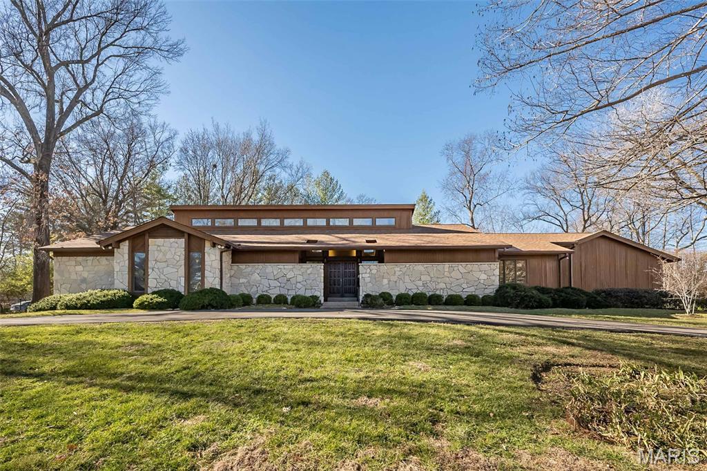 This spacious and well-appointed contemporary ranch sits on a private one-acre lot in a highly desirable Frontenac location. With over 4,000 square feet of living space on the main level, the home is designed for a comfortable lifestyle and easy entertaining.
The heart of the home is a vaulted  great room featuring a dramatic floor-to-ceiling stone fireplace, custom built-in bookshelves, and cherry hardwood floors. A large wall of windows fills the room with natural light and opens to a covered terrace that overlooks the private grounds and an in-ground saltwater pool. The main floor also includes an updated eat-in kitchen, a large formal dining room, and a private office with built-in shelving.
The expansive primary suite offers plenty of closet space and a full ensuite bath. Three additional well-sized bedrooms, another full bath, two half baths, and a laundry room are also located on the main level. For extra space, the finished lower level provides a fifth bedroom and full bath, along with a large recreation area and plenty of room for storage.
Additional features include a three-car garage, a circular driveway for easy access, 2yr old roof,  an in-ground sprinkler system. This is an outstanding opportunity for anyone looking for plenty of room and privacy in a great neighborhood and so convenient to shops, restaurants and highways!