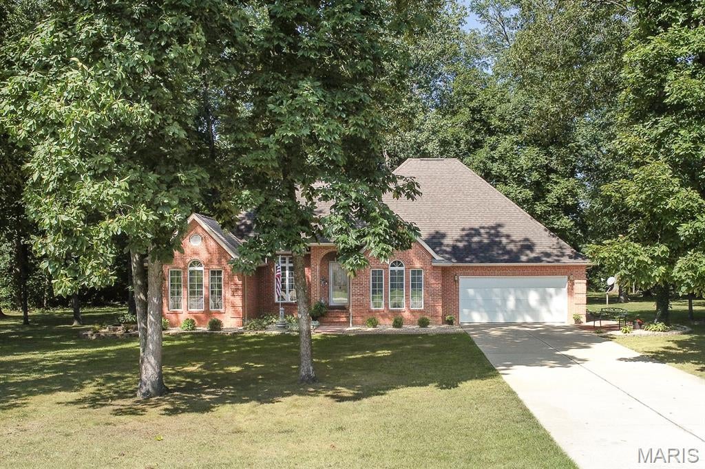 This custom-built all brick home sits on a beautifully landscaped 1-acre lot with mature trees and a private, park-like setting. The spacious living room features a fireplace and opens to a formal dining room, perfect for gatherings. The kitchen offers abundant cabinets and counter space, along with a bright breakfast room that leads directly to the patio for easy indoor-outdoor living. The private primary suite includes a bay window, walk-in closet, and a large bath with separate tub and shower. A convenient full bath is located off the hallway, along with a dedicated laundry room. Two additional bedrooms and a full bath complete the main level. Large storage area above garage and primary suite could allow for future finished living area. The oversized garage provides excellent storage and workspace. Located close to Scott AFB and area amenities. Buyer to verify all information