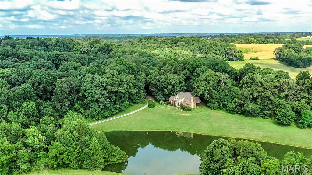 Beautiful Custom-built stone/brick home on 20 acres.  Whitetail and turkey hunting are good!
This 4 bed/3.5 bath stone and brick residence offers about 4,000 square feet of beautifully finished space.  The home overlooks a 3 acre stocked pond.  All custom cherry trim, cabinetry and solid cherry doors. The great room features a Fondulac stone gas log fireplace to add warmth and charm as well as a great view outdoors. Kitchen includes Italian quartzite countertops, cherry cabinets, center island, pantry, breakfast bar, and a casual dining space. The primary suite on the main level includes double sinks, bathtub/shower and large walk-in closet. Upstairs are 3 bedrooms, one ensuite and two share a Jack & Jill bath.  Bonus room for hobbies or another bedroom.  The main level laundry room has quartzite custom finish countertop and utility sink.  Attached 2 car garage.  A full unfinished basement includes stubbed in plumping for a bathroom.   Geothermal heating and cooling, along with an outside wood burner and an electric heat back up insure comfort.  
Outdoor living is welcoming with a brick covered back porch that overlooks the pond and scenic acreage, making it the perfect spot to enjoy morning coffee, evening relaxation, or watch wildlife roam.  There is also a covered 20X15 pavilion overlooking the pond. 
For those who need space beyond the home, the 30X60 detached shop near the residence offers endless possibilities—from a dream workshop to additional storage or hobby space—complete with loft, heat and AC and hot water floor heat.  
Whitetail deer and turkey populate the area these 20 acres that include a wooded area and two fields.  A great location for a hunter to place tree stands on his own property. 
Whether you are looking for a private country estate, hobby farm, hunting retreat, or weekend getaway, this versatile property offers space, quality construction, natural beauty, and long-term value.
Additional acreage available.
