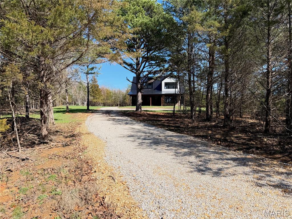 Priced Below Appraisal! Stunning Modern Farmhouse on 3.09 Acres.  Move-in ready and listed below appraised value, this exceptional new construction offers instant equity and incredible value. Nestled among mature pine trees and surrounded by woods, this modern farmhouse offers the peaceful, secluded feel of country living while remaining just minutes from town. The home's striking exterior features a durable all-metal design accented by rich cedar posts, natural stone detailing, and a spacious covered front porch that spans the length of the home creating the perfect place to relax and enjoy the natural surroundings. A 2-car attached garage provides convenient parking, storage, and easy access to the home. Inside, approximately 2,400 square feet of thoughtfully designed living space welcomes you with an open-concept floor plan and abundant natural light pouring through three oversized bay windows in the living room. The beautifully appointed kitchen serves as the heart of the home, showcasing custom maple Village Gallery cabinetry, quartz countertops, a large center island with seating and built-in electrical outlets for added convenience, and a walk-in pantry designed for both everyday living and entertaining. With 5 bedrooms and 3.5 bathrooms, this home offers flexibility for families, guests, or multigenerational living. Two private primary suites provide exceptional comfort, including a main-level suite featuring a walk-in closet and en-suite bath, plus a second upstairs suite with its own full bathroom. The main floor also includes a guest bath and laundry room, while upstairs offers three additional bedrooms, a full bath, and a convenient second laundry closet. The 3.09-acre property offers plenty of room to expand and make the space your own. A large open side yard on the south side of the home provides an ideal location for a future detached garage, workshop, storage shed, greenhouse, garden area, or additional outdoor living space. The property also benefits from two separate access points, with entrances from both County Road 4110 and County Road 4180, providing added convenience, flexibility, and ease of access. Whether you're looking for room for hobbies, equipment, gardening, or future improvements, this property offers endless possibilities. Combining timeless farmhouse style, modern finishes, and a private wooded setting, this one-of-a-kind property delivers the perfect balance of comfort, convenience, and country charm. Additional acreage is available for purchase.