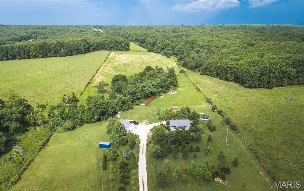 Tucked away on 10 beautiful acres just minutes from Rolla, this newer custom-built home offers the perfect blend of privacy, comfort, and country living. Surrounded by mature ornamental trees, native landscaping, and peaceful scenery, the property feels like your own private retreat while still being conveniently close to town. A gated driveway leads you into this secluded setting where deer frequently travel through the property and a wet weather creek winds through the land. The home features quality craftsmanship throughout with custom tile work, granite countertops, solid wood doors, warm car siding interior finishes, and durable metal roofing. Covered porches provide the perfect place to relax and enjoy the quiet surroundings year-round. Outside, the swimming pool creates an ideal setup for entertaining and enjoying summer days. A 24x32 insulated detached shop offers excellent space for projects, storage, or equipment, while three additional metal sheds/barns provide endless possibilities for livestock, hobby farming, workshops, or recreational use. Whether you are looking for a full-time residence, mini farm, or private country getaway, this property offers a rare combination of beauty, functionality, and seclusion in a highly desirable location near Rolla.