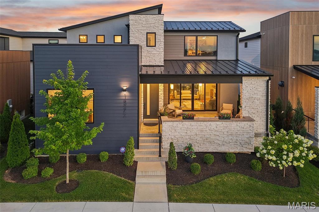 Built in 2023 by McKelvey Homes, this custom contemporary home sits on the water in Waterfront at Wildhorse Village, one of only 35 custom contemporary/modern homes in the enclave. A design concept without comparison elsewhere in the St. Louis region. This northwest facing, 4-bedroom, 2.5-bath home offers 2,684 sq ft with Pella windows offering serene lake views from the living room, kitchen, office and one upstairs bedroom. Large sliding glass doors open the living room to a front covered lanai for indoor/outdoor living directly over the water, while a covered back porch overlooks a private courtyard complete with a fireplace, arbors, a footbridge, and mature plantings and hardscape. The living room is wired for beautiful sound with a premium integrated sound system that will be staying with the home.  
The kitchen is built around an expanded waterfall-edge island with a Wolf gas cooktop with a noise-reduced downdraft vent, floor-to-ceiling two-tone cabinetry with crown molding, GE Cafe French door wall mount ovens double wall ovens, Samsung Bespoken refrigerator with beverage center, and quartz countertops. The adjoining dining area opens to the courtyard and includes a serving area with a wine fridge and matching quartz counters. A walk-in pantry with convertible Galanz retro fridge/ freezer and walk-in laundry room with GE washer and dryer with under storage sit just off the kitchen, with a main-level office/front bedroom and half bath completing the floor plan. A covered breezeway links the back-loaded 3-car garage to a landing space, the primary bedroom, and the kitchen for direct main-level access. The garage is prepared with a 50-am receptacle for an EV charger should you desire. 
The main-level primary suite includes a soaking tub, large shower, private toilet room, double vanities, and a walk-in closet with a custom closet system, with the bedroom itself facing the courtyard. A convenient access from the primary ensuite to the garage was added to the floor plan for functionality. 
Upstairs, two additional bedrooms, a full bath, and a study nook complete the home; the lower level is unfinished, with an egress window and bath rough-in already in place.
The community sits adjacent to two small lakes, with parks and recreational trails nearby, Chesterfield Amphitheater approximately 0.5 mi away, and a YMCA approximately 0.2 mi away. I-64 access is approximately 1 mi out, and The District and Chesterfield Commons shopping complex is approximately 2 mi away. The ongoing Chesterfield Mall redevelopment — a planned $2 billion, 4.5-million-square-foot mixed-use project with a central park, residential units, retail, dining, and entertainment — is positioned to become Chesterfield's new downtown. Includes 3D walkthrough and floor plan.