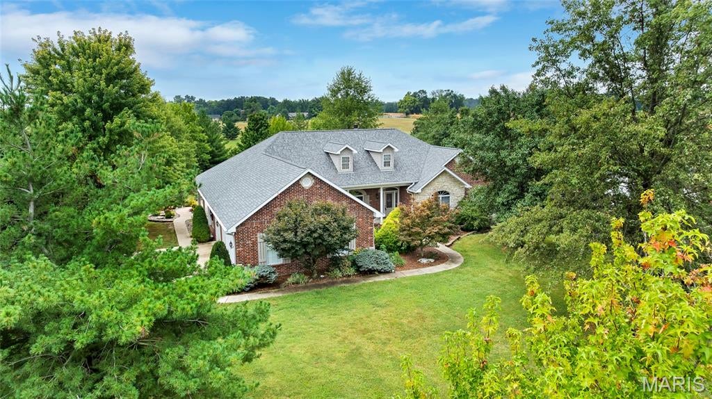 A rare opportunity to own an exceptional country estate where refined finishes meet over 5 rolling acres of picturesque grounds. Thoughtfully designed for both elegant entertaining and everyday comfort, this impressive home showcases hardwood floors, custom built-ins, two fireplaces, a formal dining room, and a gourmet kitchen appointed with granite countertops, staggered cabinetry, and glass display inserts.

The main-floor primary suite feels like a private sanctuary with a spa-inspired bath and its own covered patio—perfect for quiet mornings overlooking the property. The finished walkout lower level expands the home's possibilities with a custom bar, generous entertaining space, private bedroom suite, and abundant storage.

Beyond the home is where this property truly sets itself apart. Over 5 acres of rolling ground, extensive landscaping, and established fruit trees create a beautiful setting with room to spread out, entertain, garden, or simply enjoy the privacy of country living. The substantial outbuilding, complete with its own water and separate 100-amp electric service, offers incredible versatility—ideal for a serious workshop, collector car storage, hobby space, studio, equipment, recreational toys, or the ultimate home base for your passions. A three-car garage provides even more space for vehicles and storage.

Geothermal heating and cooling, central vacuum, multiple outdoor living areas, and quality finishes throughout complete this remarkable offering. Private, versatile, and beautifully appointed, this is more than a home on acreage—it's the kind of property that rarely comes to market.