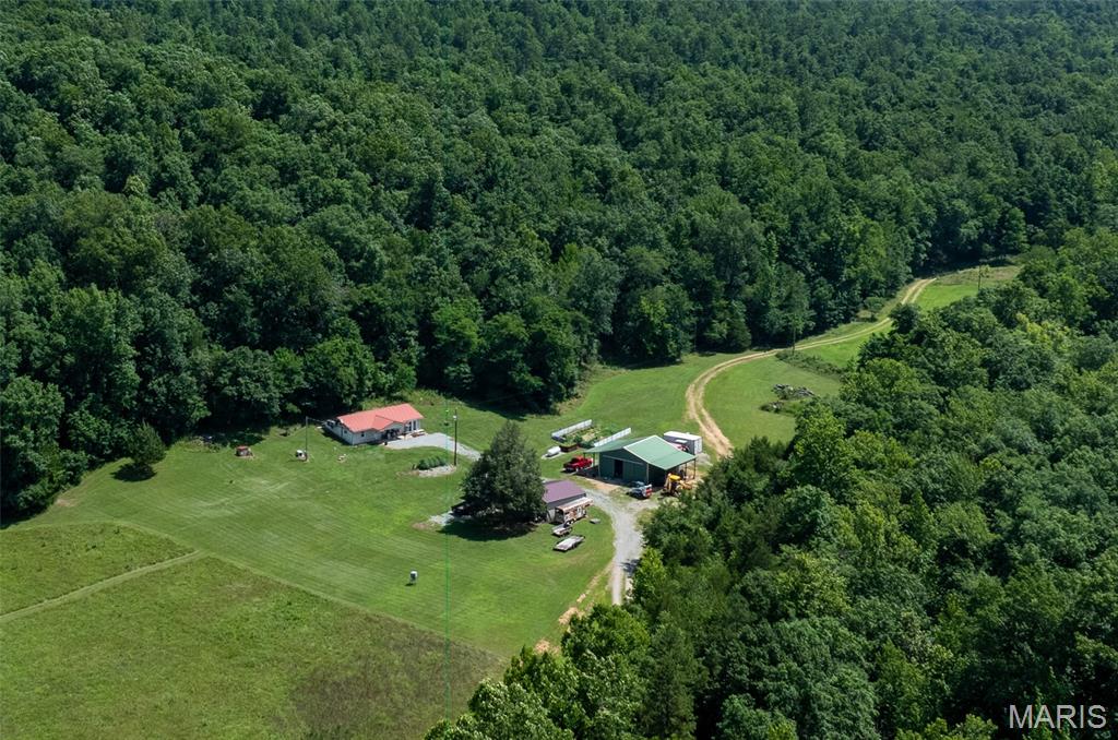 This stunning 72-acre retreat offers an ideal blend of beauty and privacy, featuring a newly remodeled home that spans 1,104 square feet, complete with two bedrooms, one bathroom, a kitchen, and an office. The residence provides breathtaking views of the valley below and is complemented by a newer two-car detached garage and a spacious 30 x 30 shop. Equipped with modern amenities such as heating and air conditioning, new siding, and windows, the home also includes a backup generator for power outages and its own well, along with an RV hookup for added convenience. Note there is an easement across property for access to farm behind. Very seldom used but does cross property.  The property is enhanced by a dry creek that meanders through the land, eventually flowing into the popular 12-Mile Creek, a favored summer destination for water activities. With a harmonious mix of wooded areas and open fields, this farm is an excellent hunting ground, featuring established shooting house and tree stands, all managed for mature deer populations that frequent the area. The land has previously supported food plots, particularly in the fall, and boasts a healthy turkey population, with bears also spotted in recent years, making it a hunter's paradise. It is important to note that while there are low water crossing to access the home and a floodplain along the creek, the residence and its buildings are situated outside of the floodplain. The picturesque and secluded setting surrounding the home resembles a scene from a movie, offering an enchanting escape into nature.