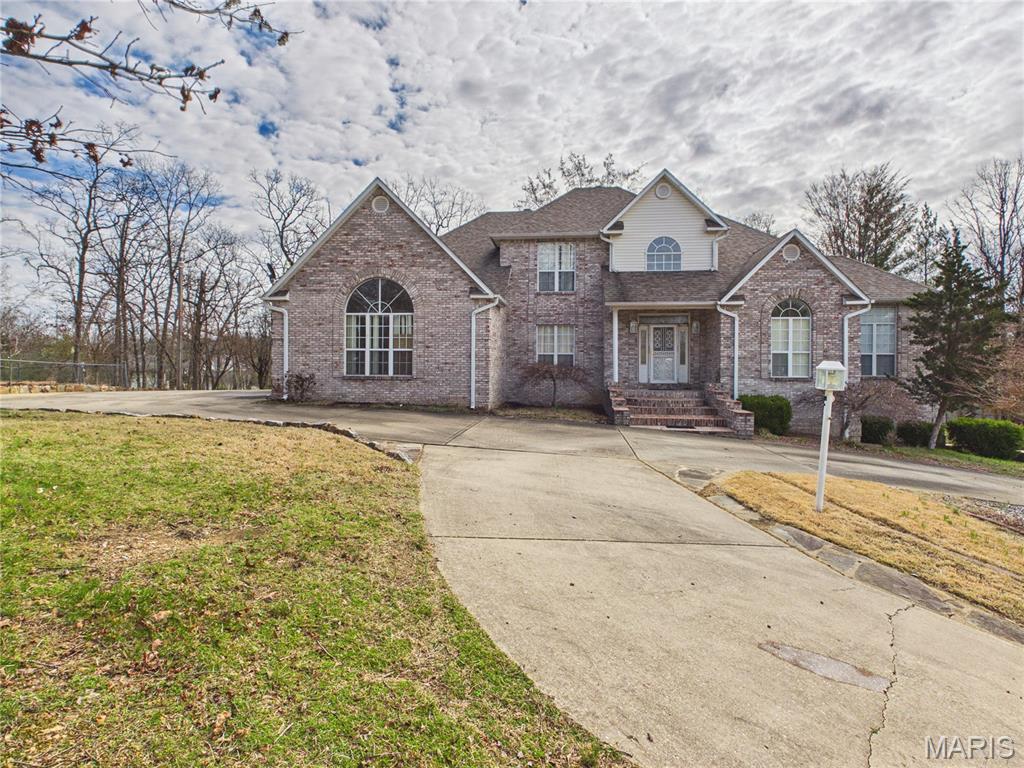 Welcome to this stunning 6-bedroom, 3.5-bath brick home offering space, style, and functionality in every square foot. Nestled on a gently sloping lot with a circle driveway, this residence features a stately facade with a covered front porch and a shaded back deck, perfect for relaxing or entertaining. Step inside to a dramatic two-story foyer that opens into a sunken living room with a cozy fireplace and abundant natural light. The main level boasts a spacious primary suite with a private bath, a dedicated home office, formal dining room, breakfast nook, pantry, and a well-equipped laundry room for ultimate convenience. Upstairs, you’ll find three generous bedrooms and a full bath, while the full finished basement offers even more living space with two bedrooms, a full bath, a second kitchen, dining area, great room with fireplace, and a safe room, ideal for multi-generational living or hosting guests. With tall ceilings, custom finishes throughout, and ample storage, this home checks every box for luxury and comfort. The 3-car garage adds even more convenience. Located in the back corner of Stone Ridge Subdivision, the property is just minutes from the conveniences of shopping, schools, and hospitals. A true must-see!